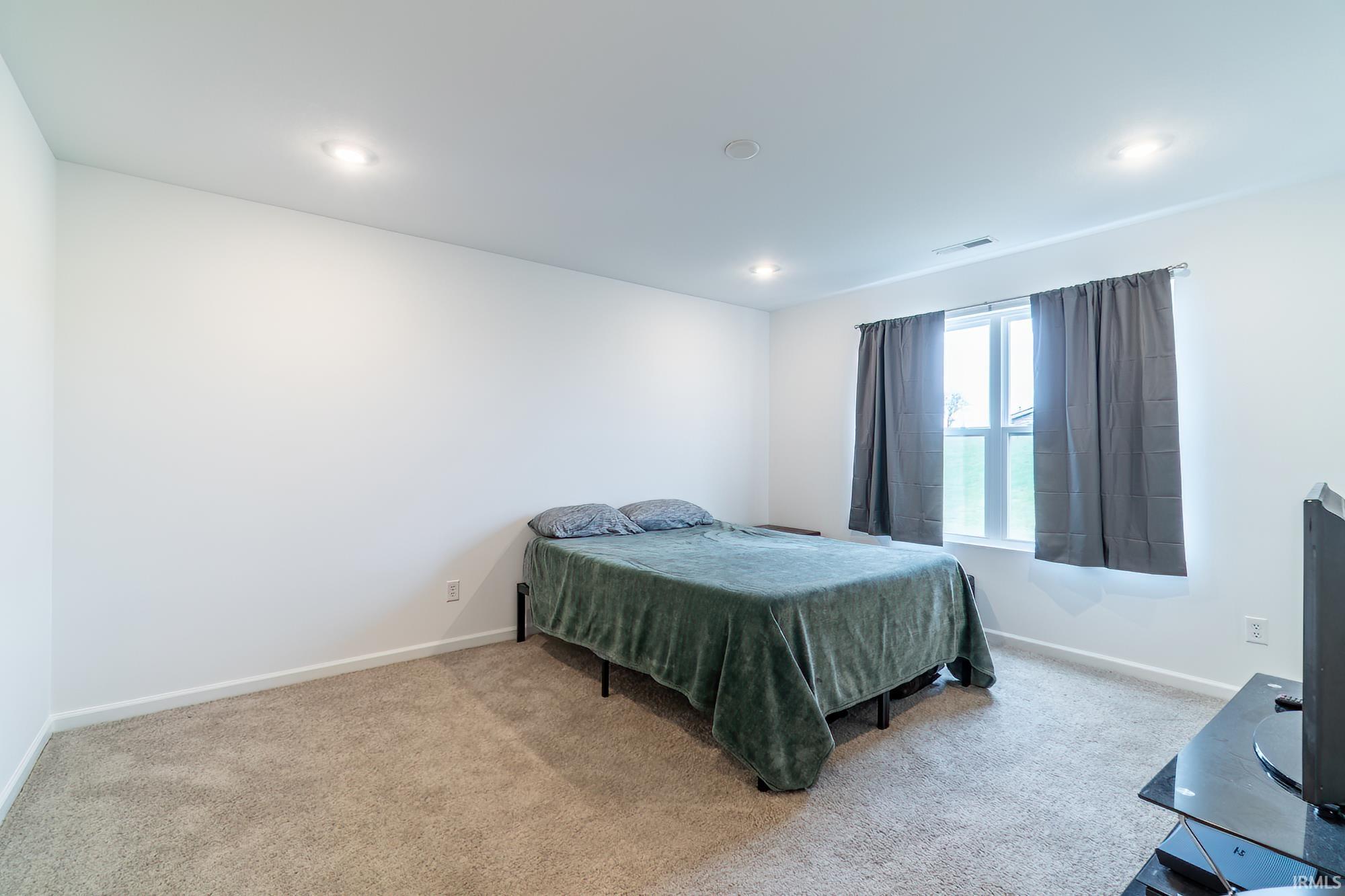Bedroom with light colored carpet and recessed lighting