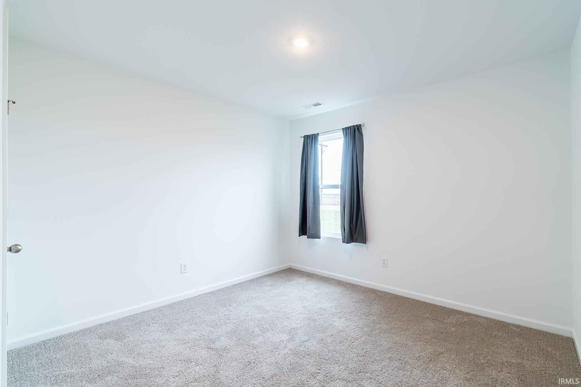 Carpeted spare room featuring baseboards