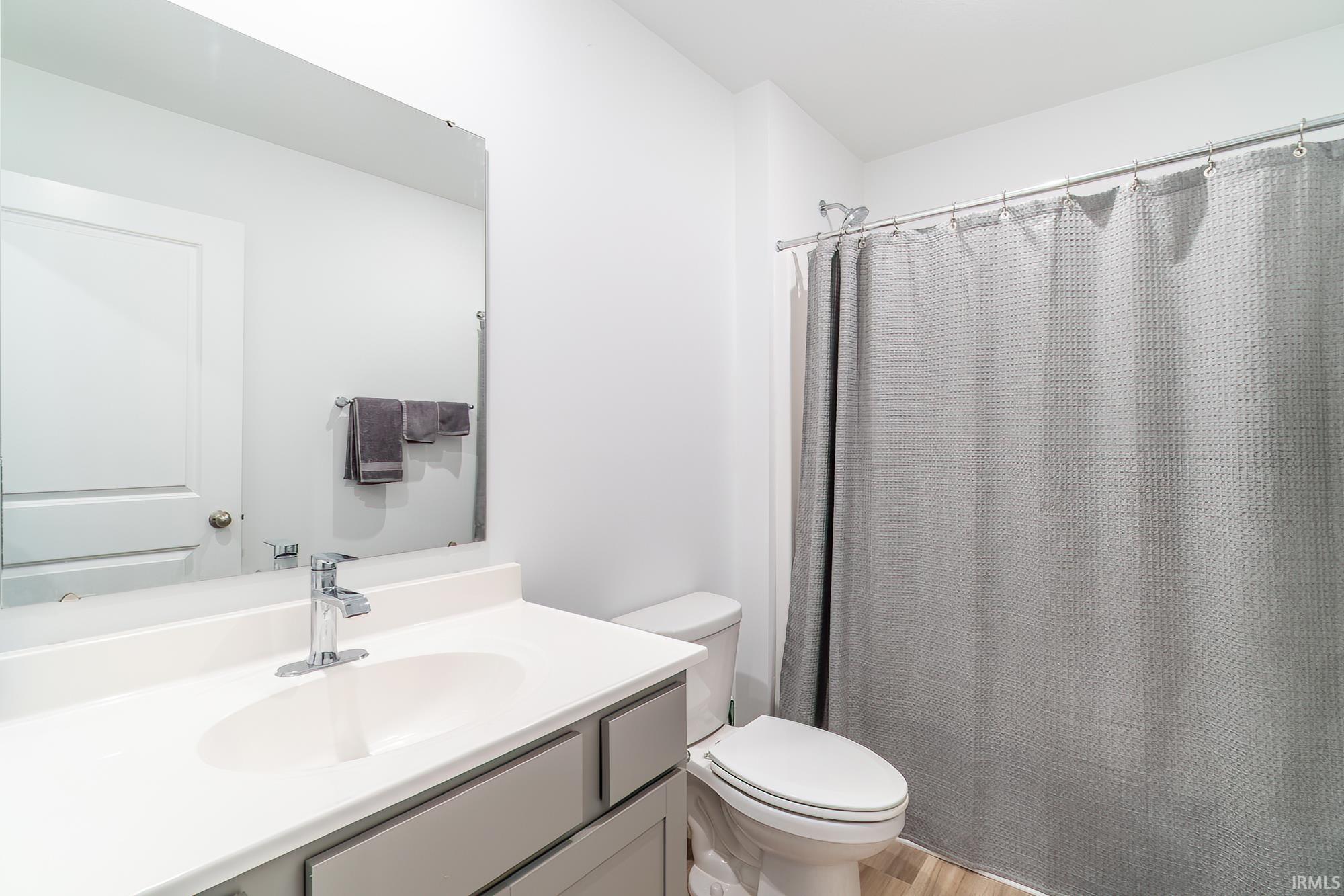 Full bath featuring vanity, a shower with curtain, and light wood-style floors