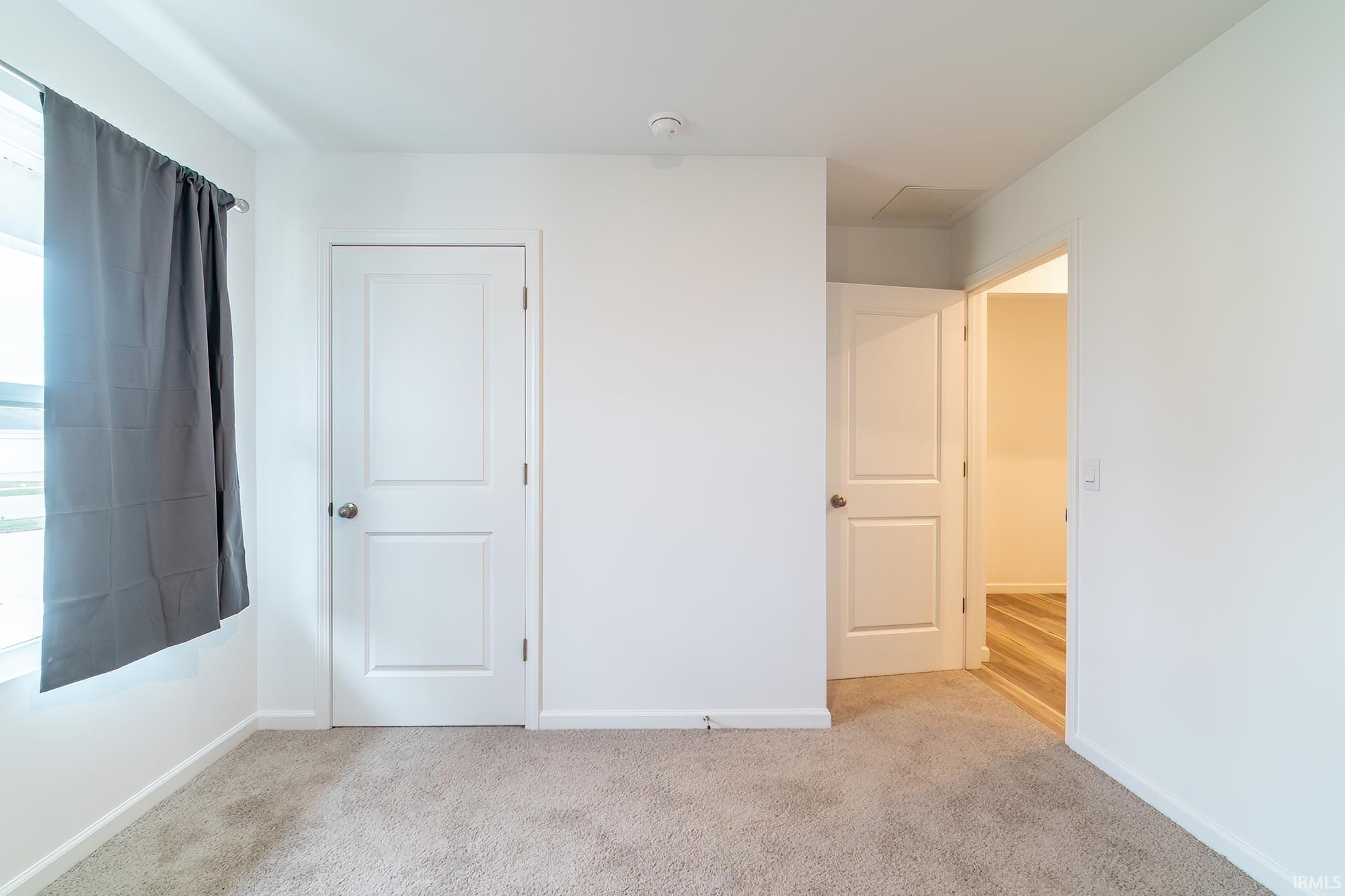 Unfurnished bedroom with baseboards and light colored carpet