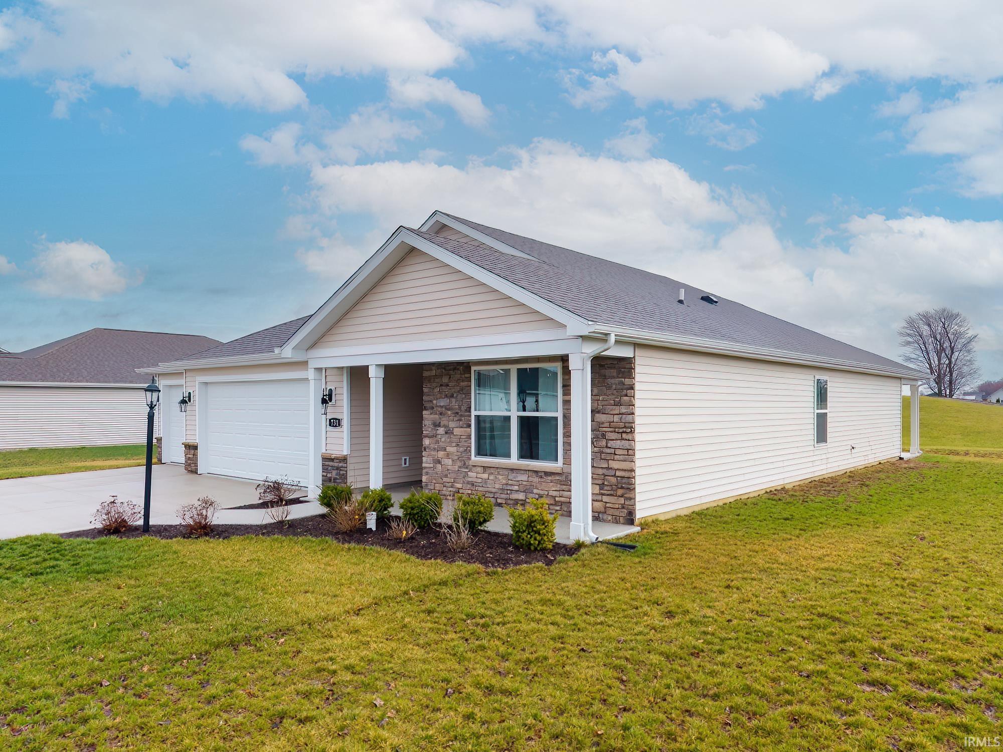 Single story home featuring a front yard, driveway, a garage, stone siding, and a porch