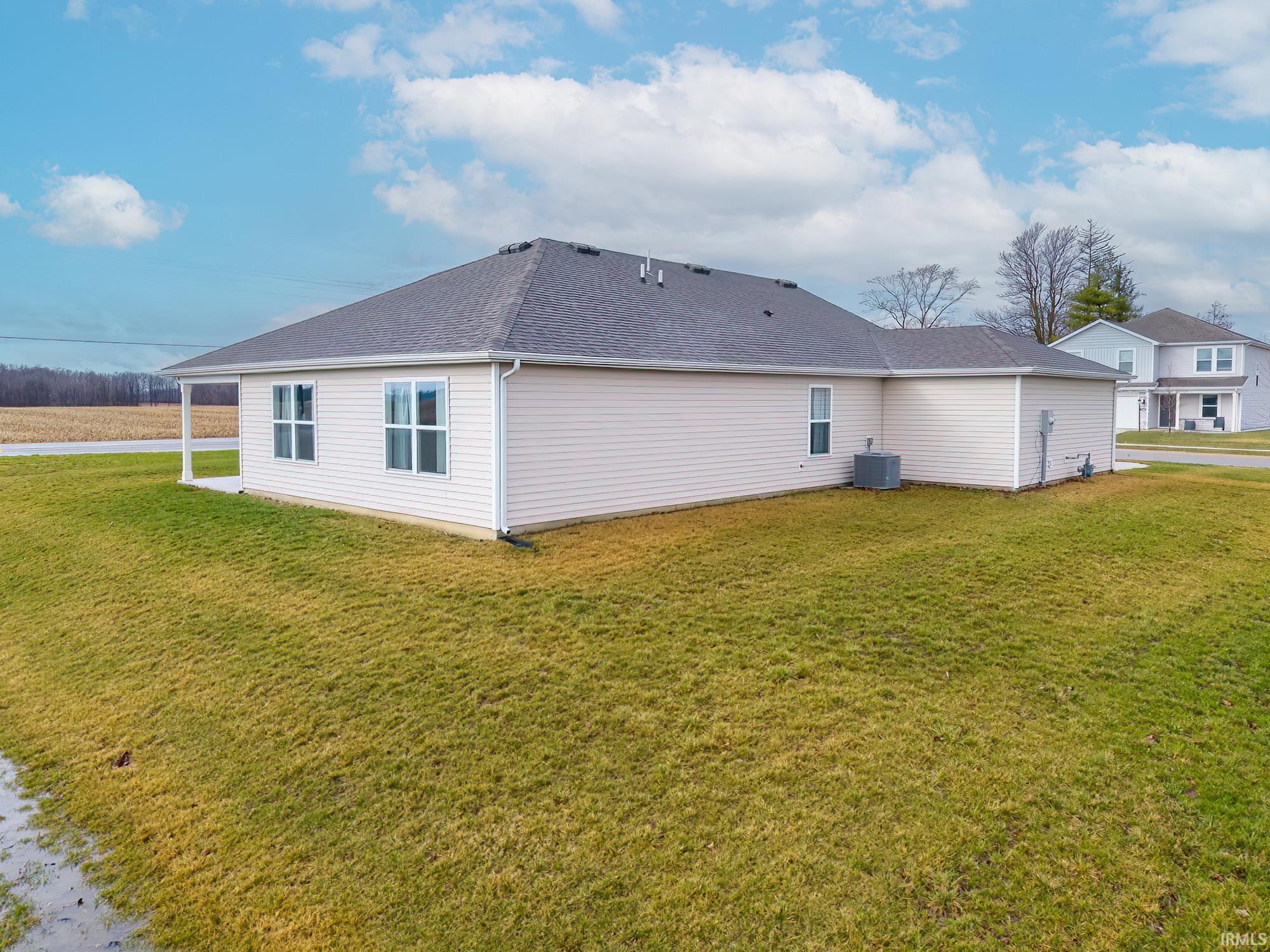 Back of house featuring roof with shingles and a lawn