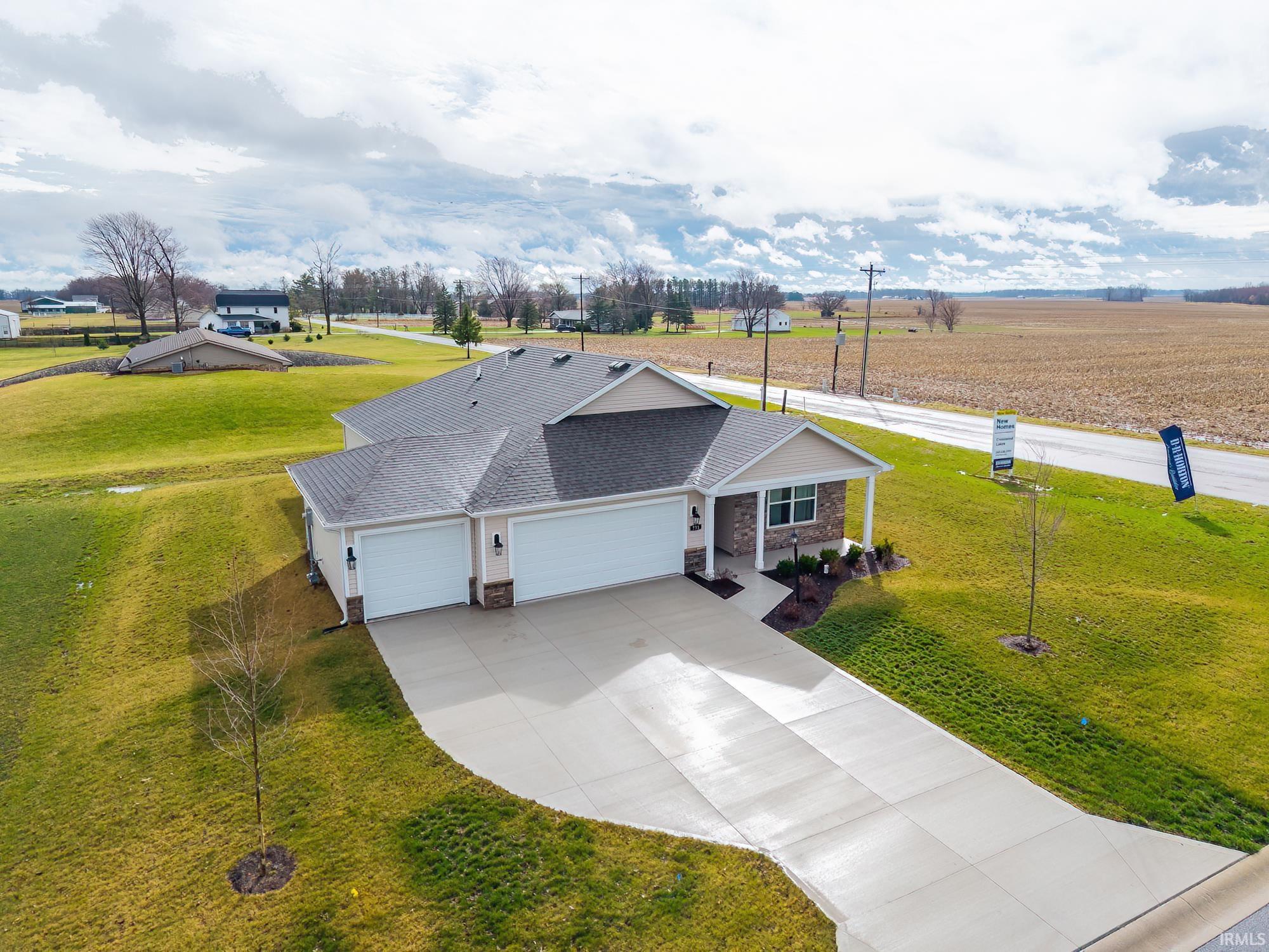 View of front facade featuring an attached garage, a front yard, concrete driveway, and a shingled roof