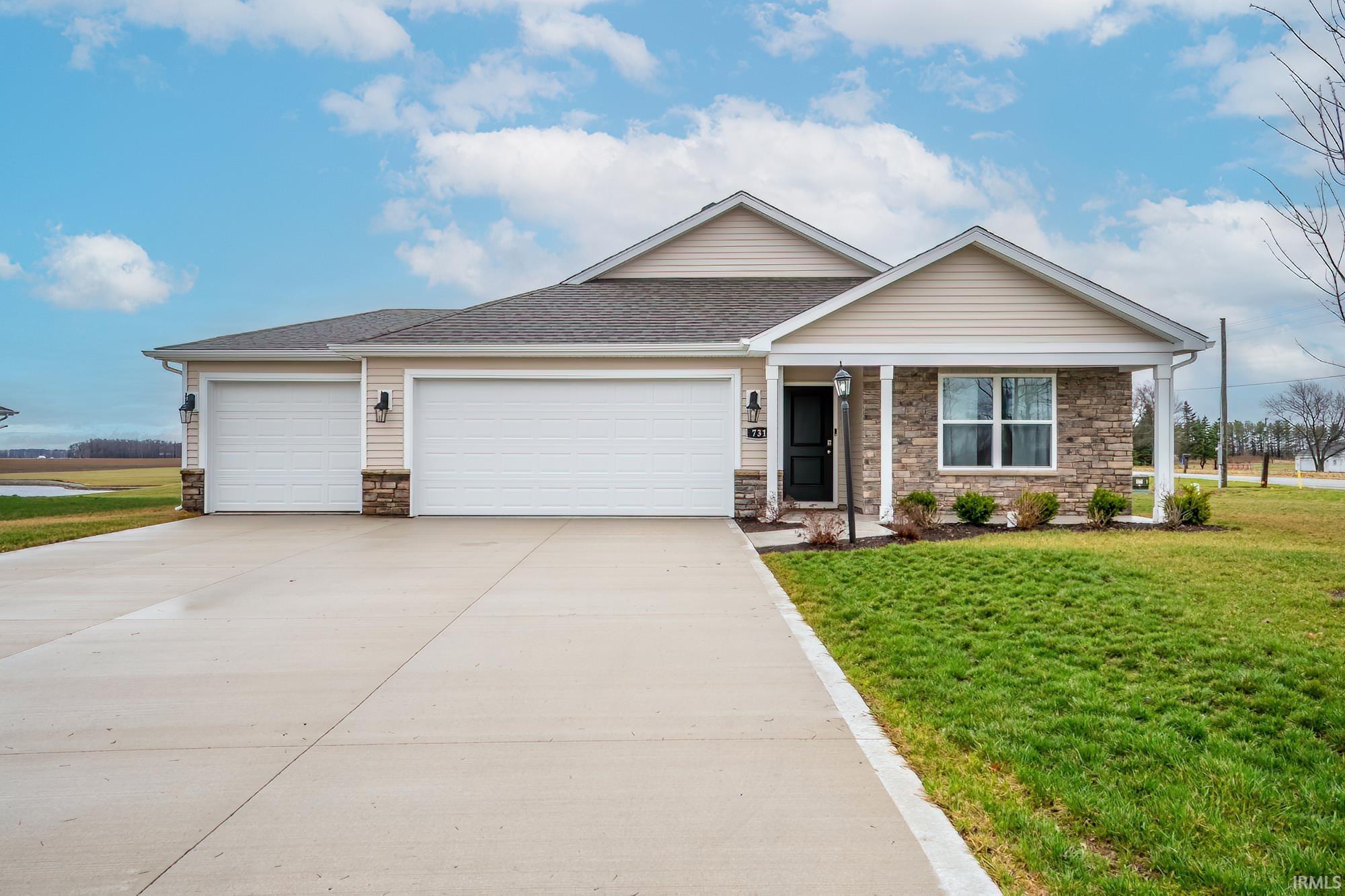 Ranch-style house featuring stone siding, a garage, and a front yard