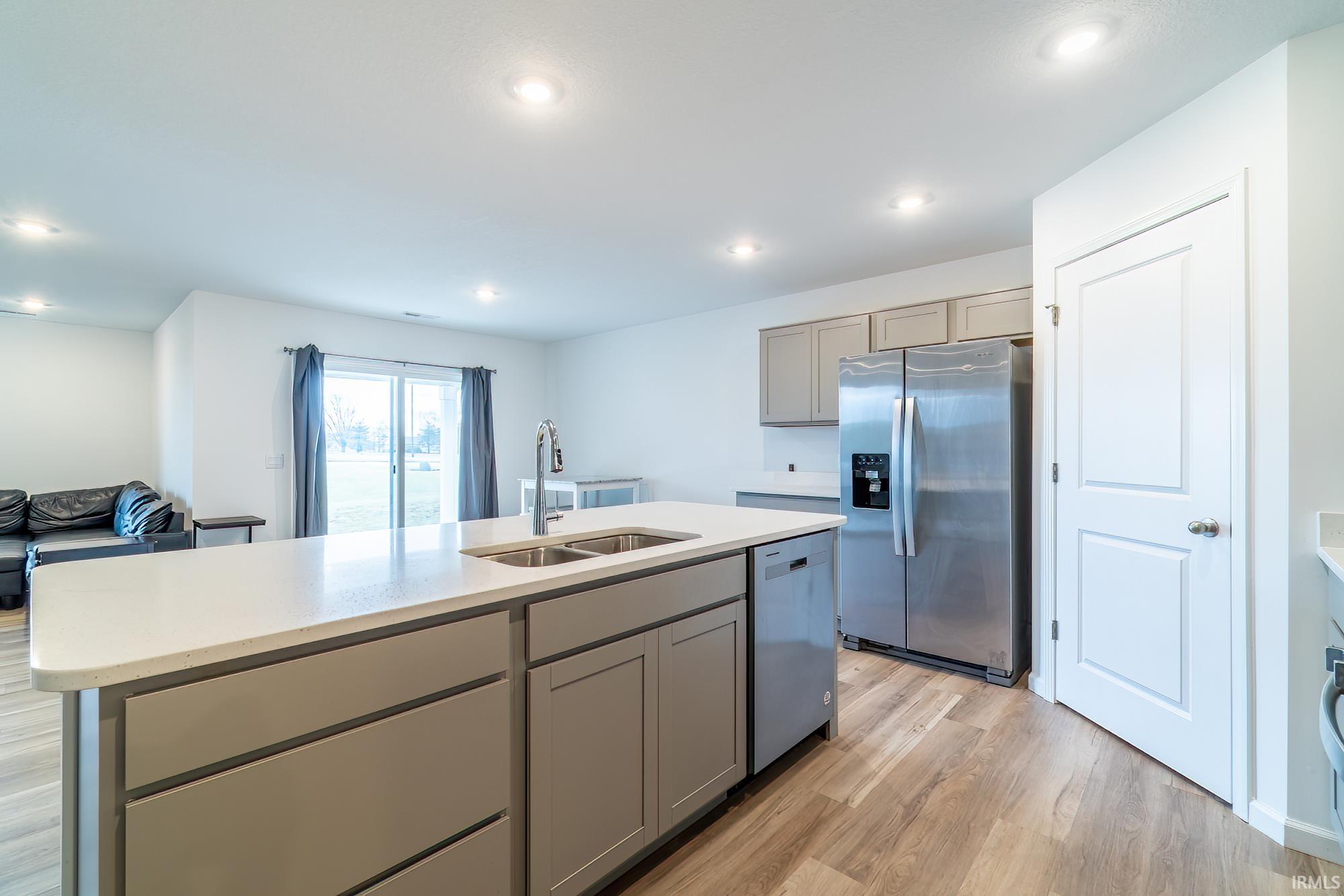Kitchen featuring stainless steel appliances, gray cabinets, light wood-style flooring, a kitchen island with sink, and recessed lighting