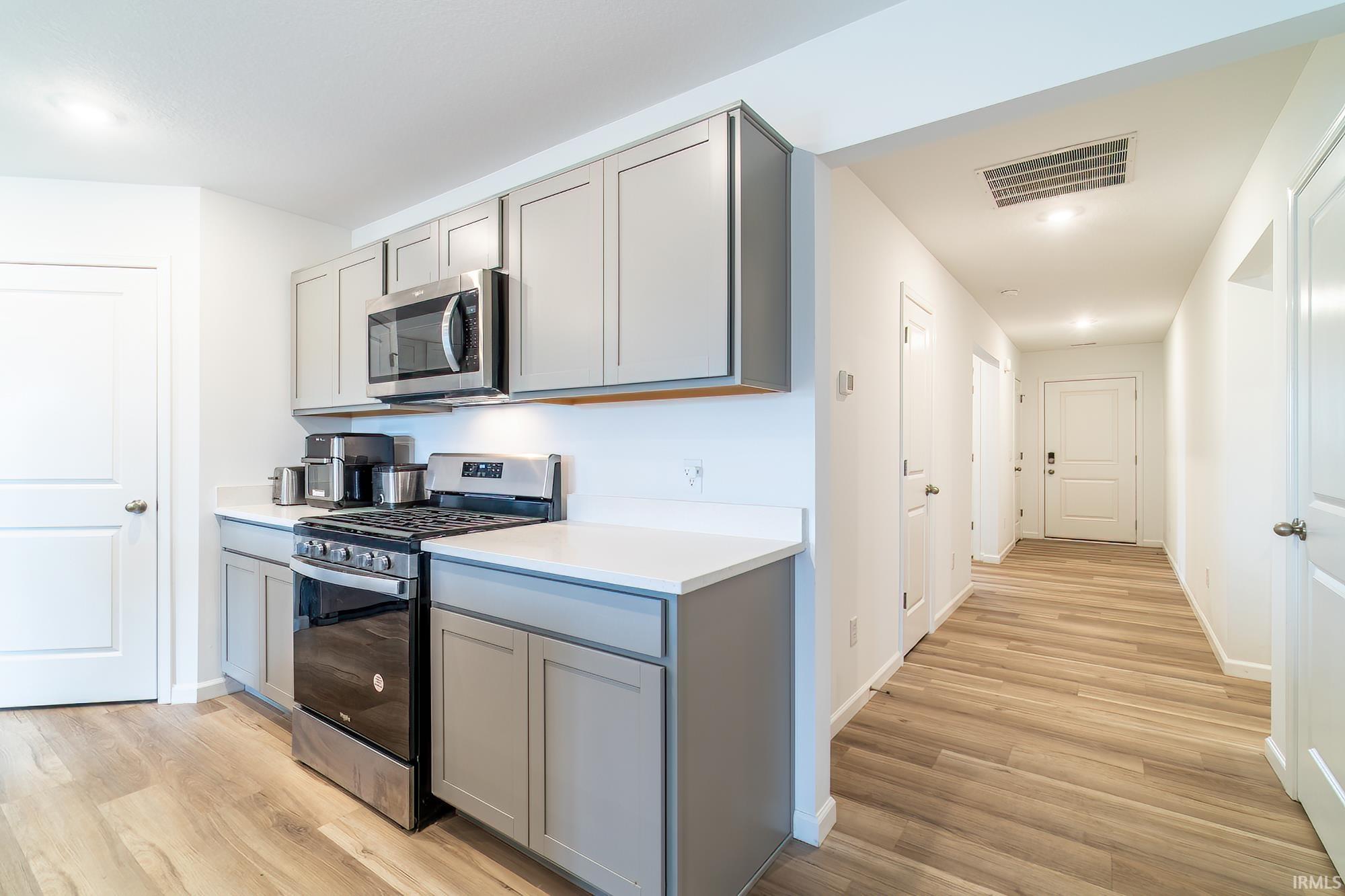 Kitchen featuring gray cabinets, stainless steel appliances, light countertops, light wood-style floors, and recessed lighting