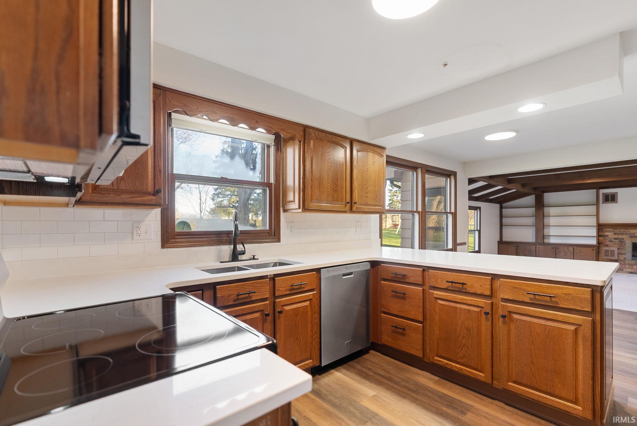 Kitchen with electric range, wood finish cabinets, light countertops, a peninsula, and recessed lighting