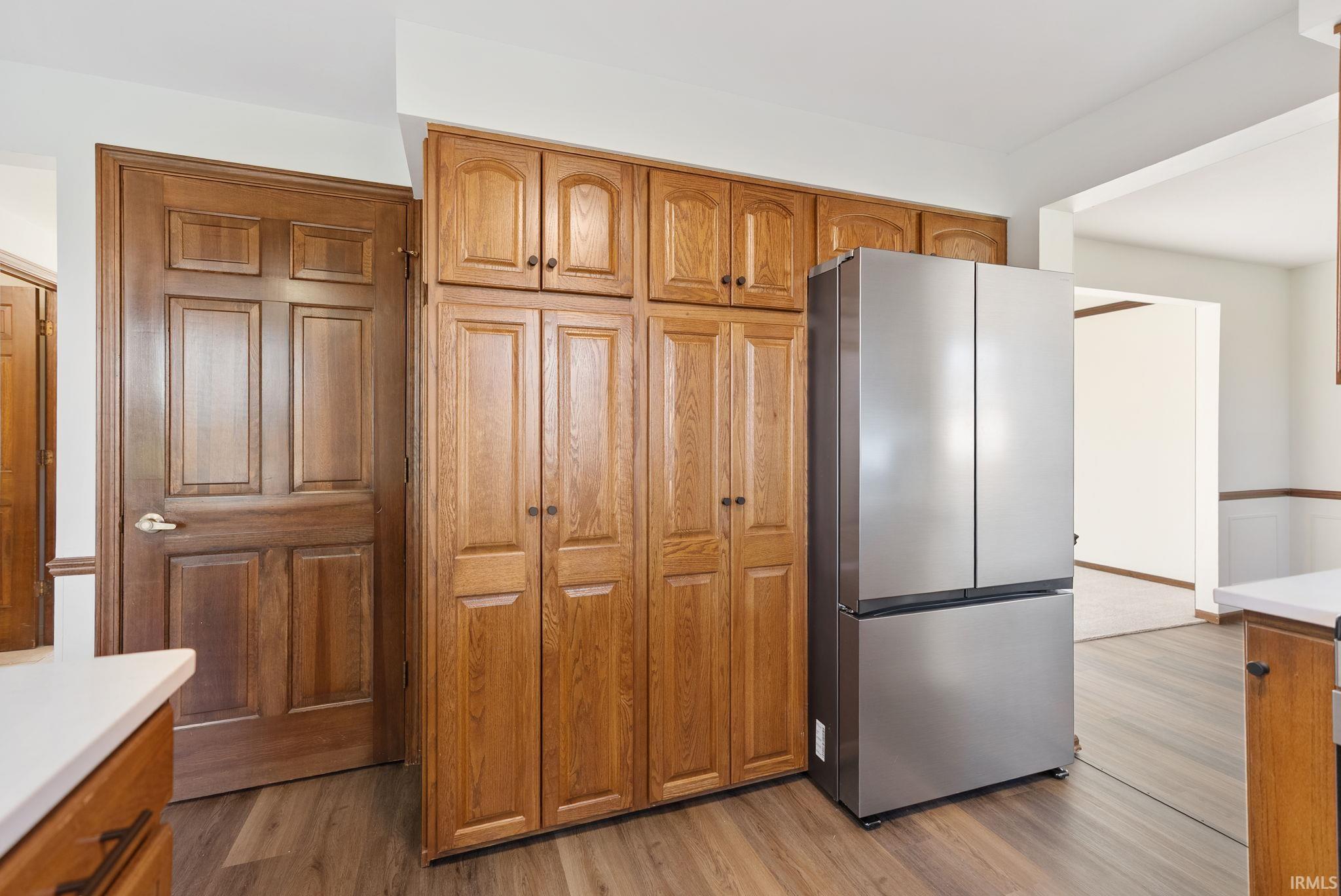 Kitchen with wood finish cabinetry, freestanding refrigerator, light wood finished floors, and light countertops