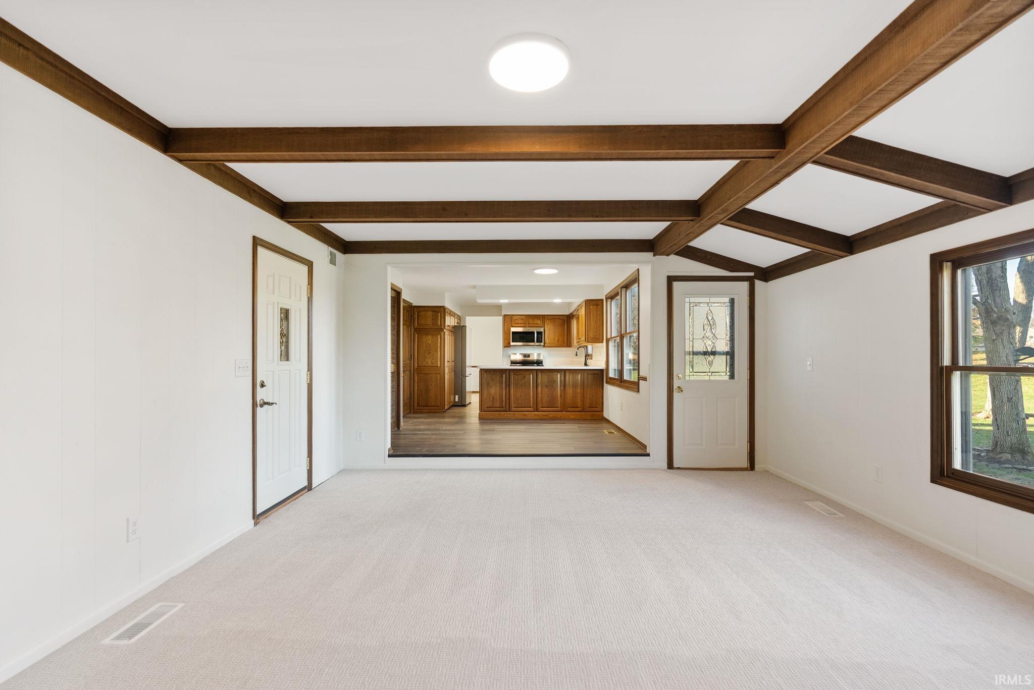 Unfurnished living room with light carpet and beam ceiling