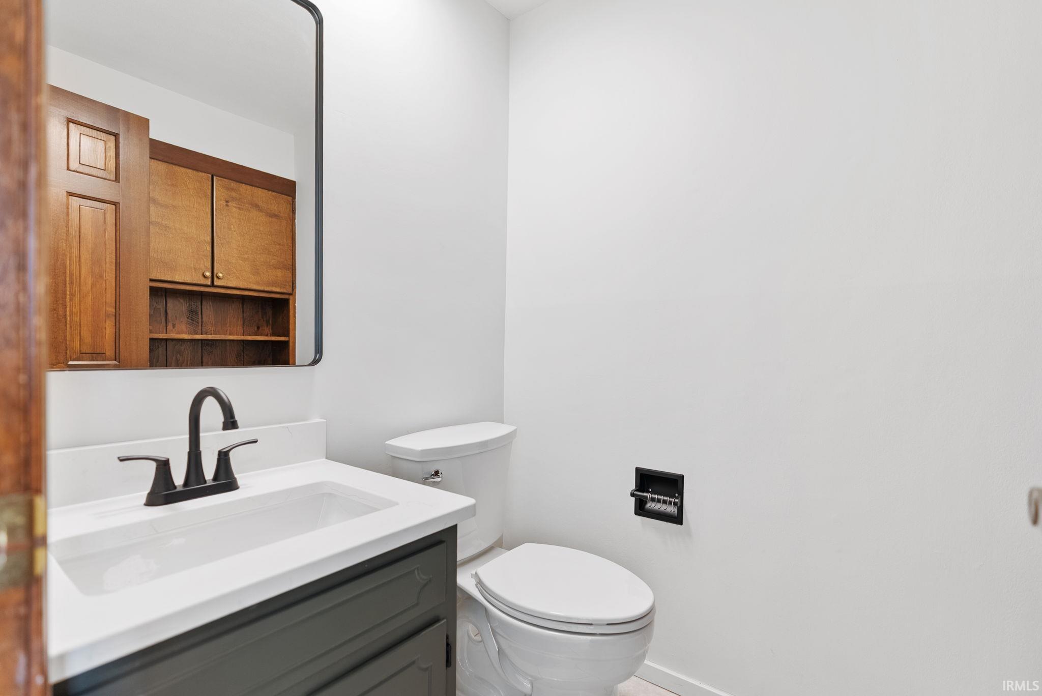 Half bathroom featuring vanity and toilet