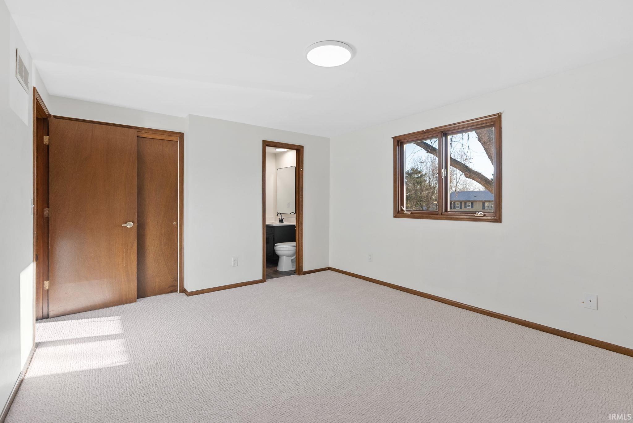 Unfurnished bedroom featuring a closet, carpet floors, and connected bathroom