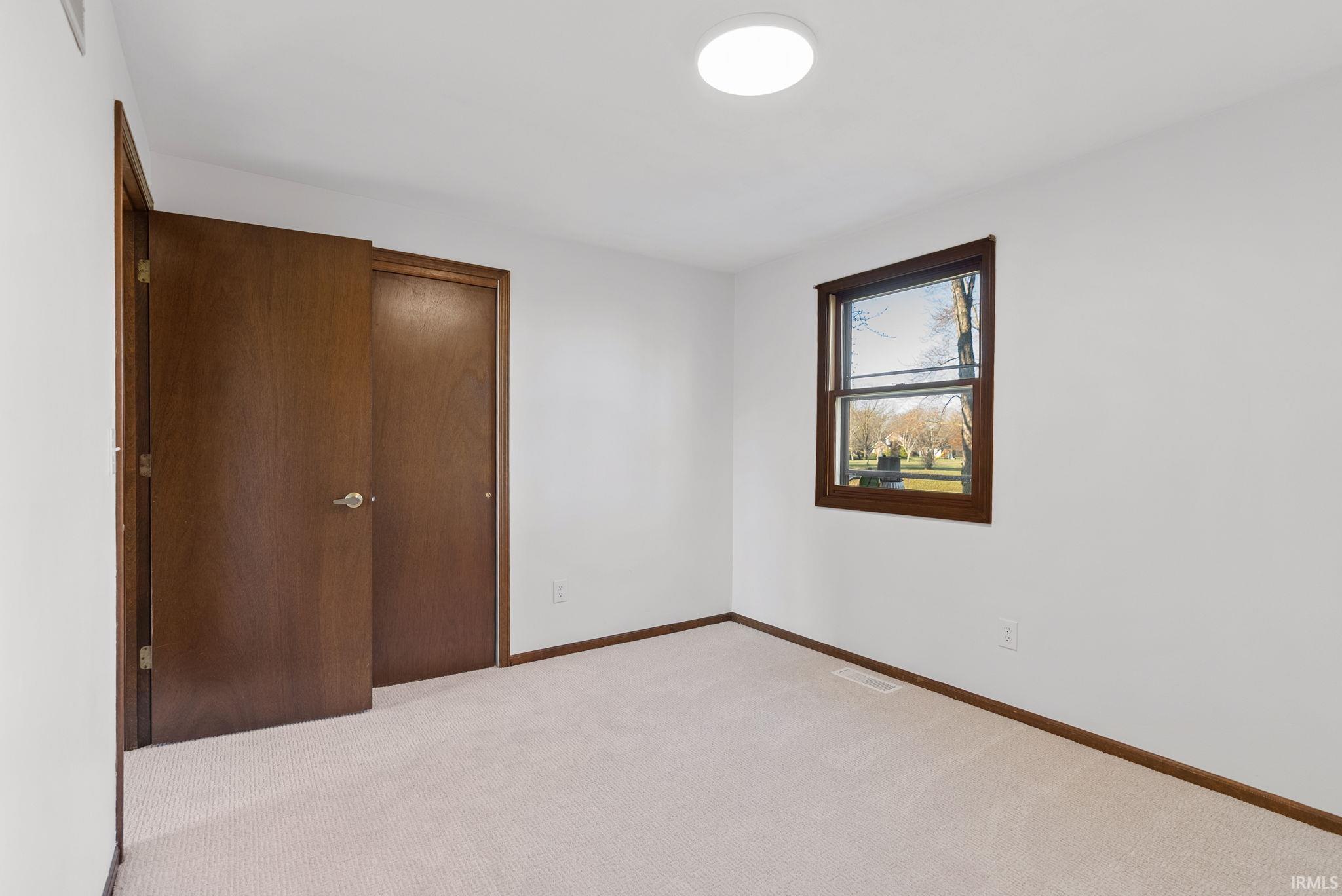 Unfurnished bedroom featuring a closet and light colored carpet