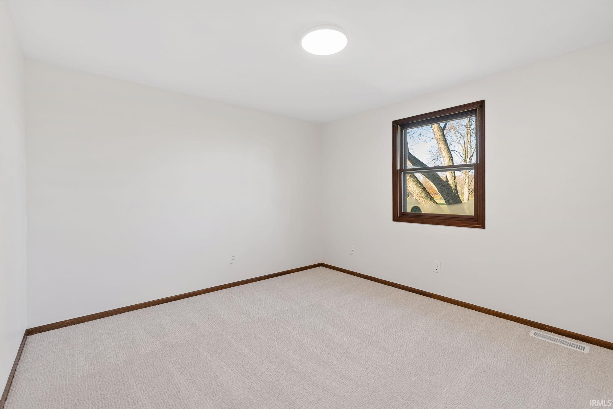 Empty room with light colored carpet and baseboards