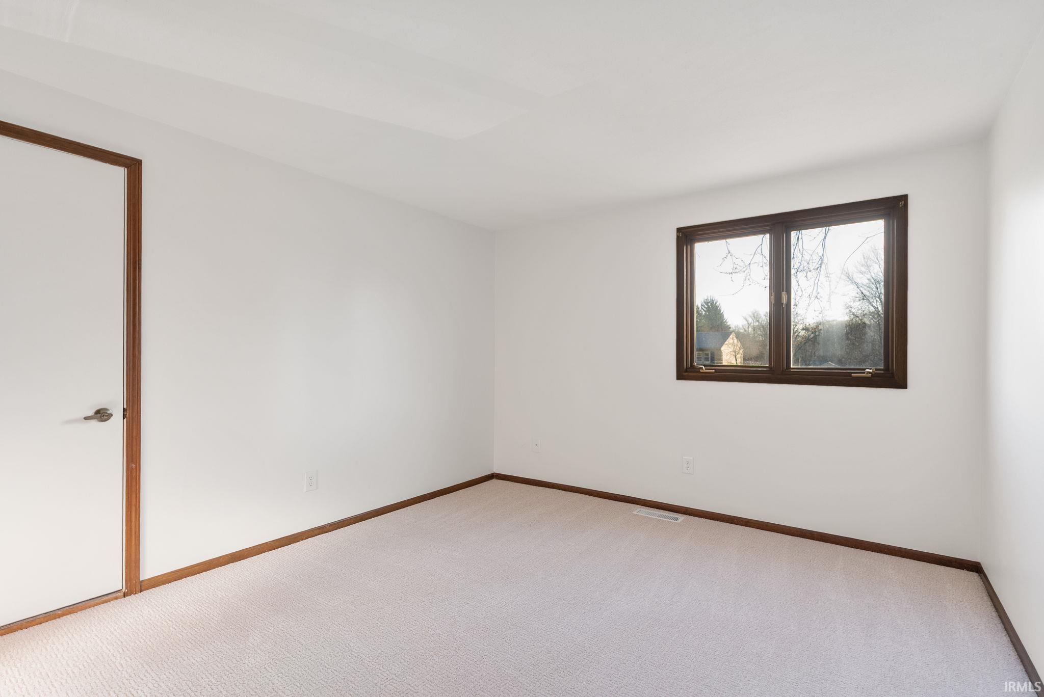Empty room with light carpet and baseboards