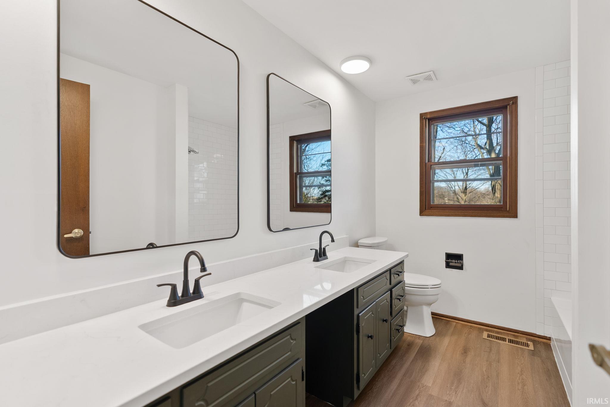 Bathroom with double vanity and dark wood finished floors