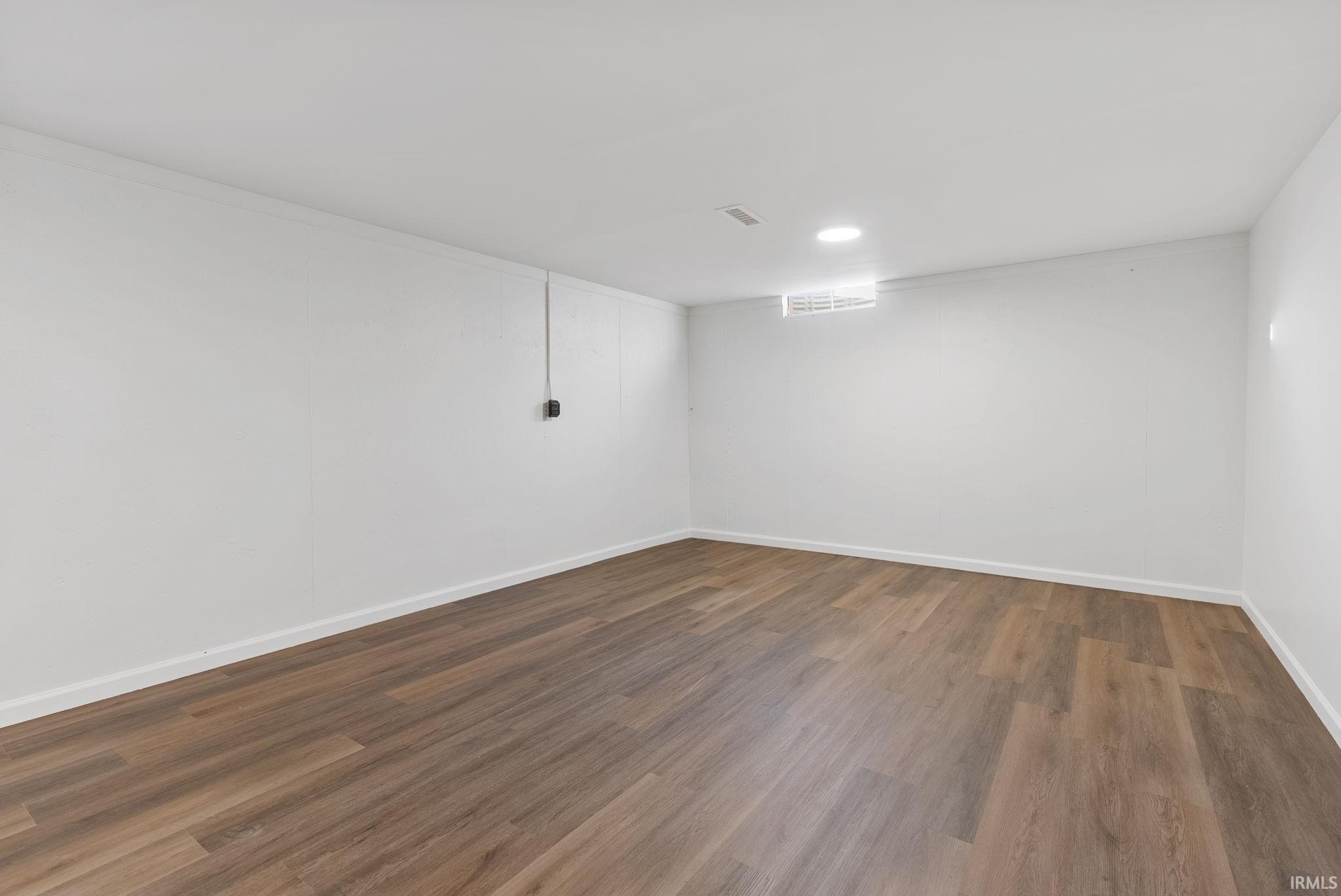 Finished below grade area featuring dark wood-type flooring and recessed lighting