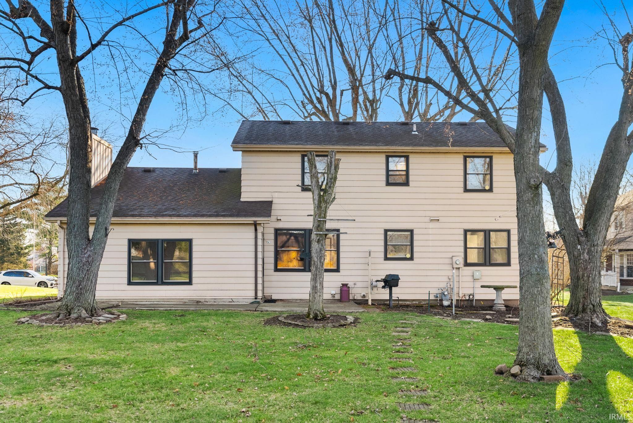 View of front of house featuring a front lawn, a patio, and a shingled roof