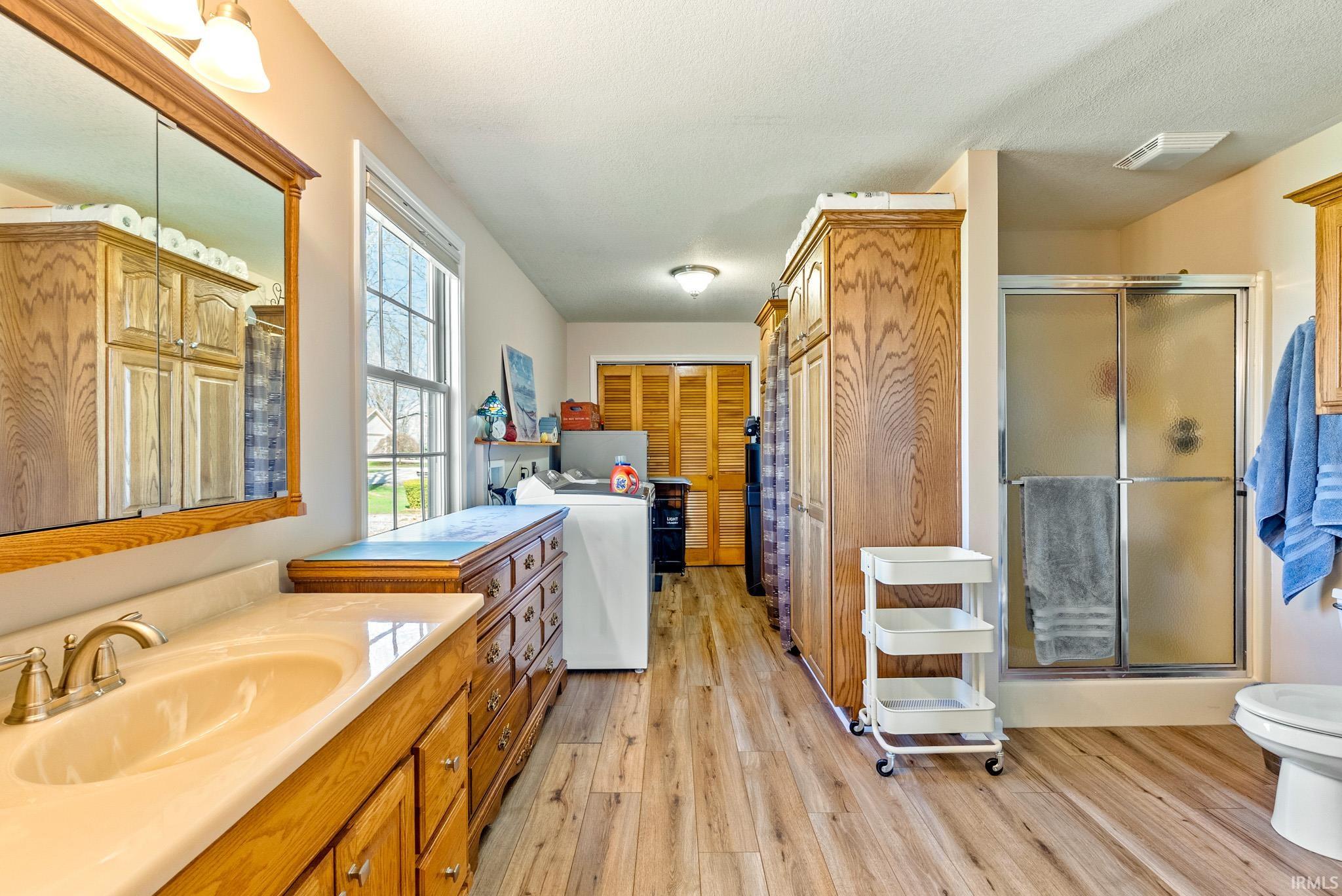 Full bathroom featuring vanity, a stall shower, a closet, and light wood-style floors