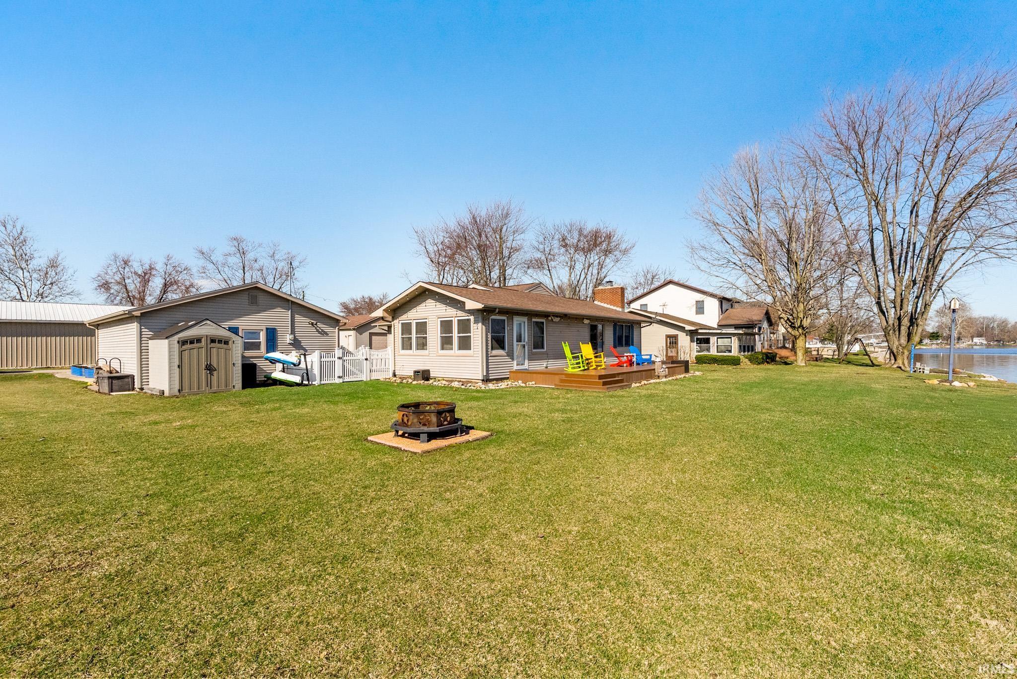 Rear view of house with a storage shed, a fire pit, a deck, and a yard