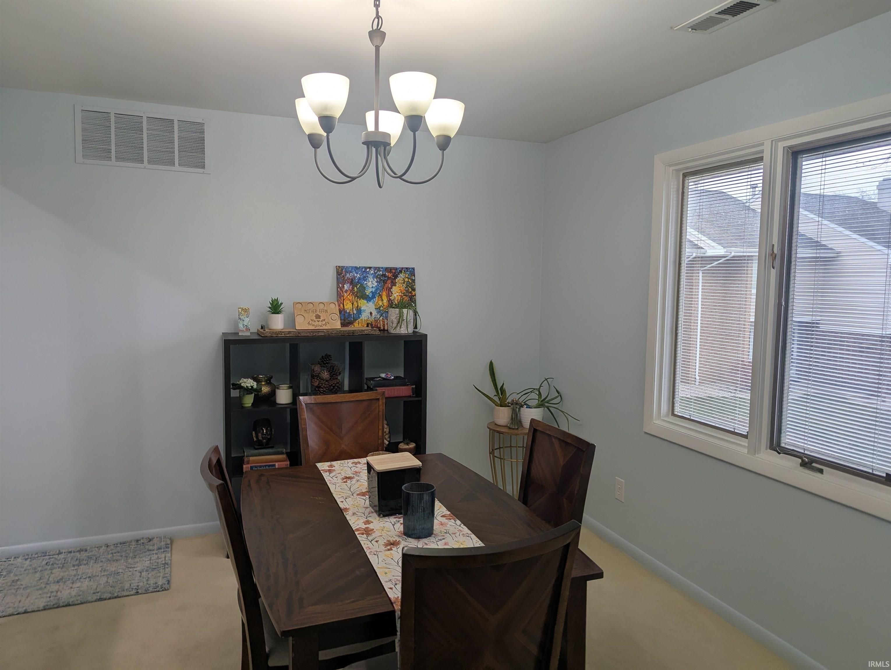 Carpeted dining room with a chandelier and baseboards