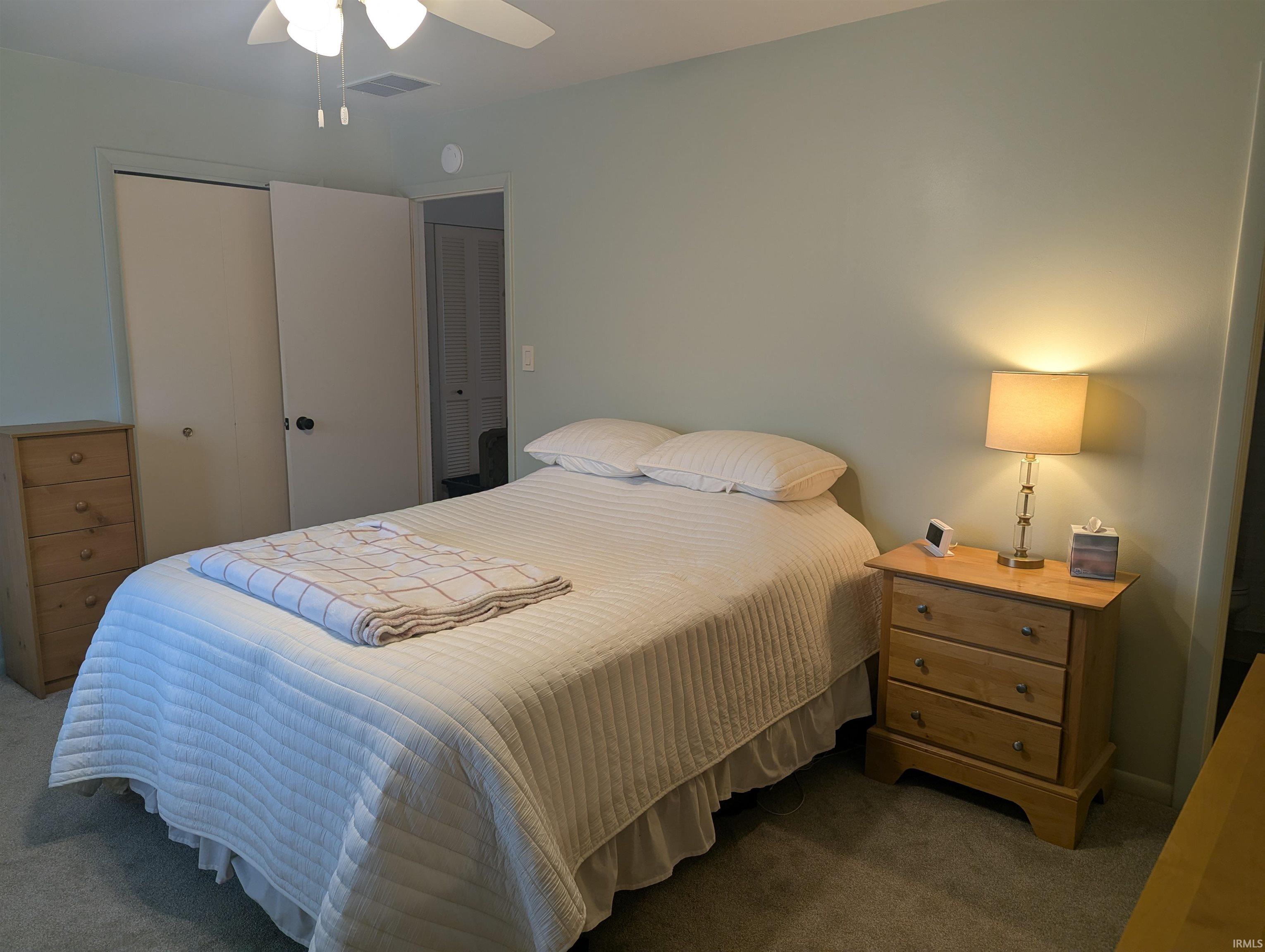 Bedroom with dark carpet, a ceiling fan, and a closet