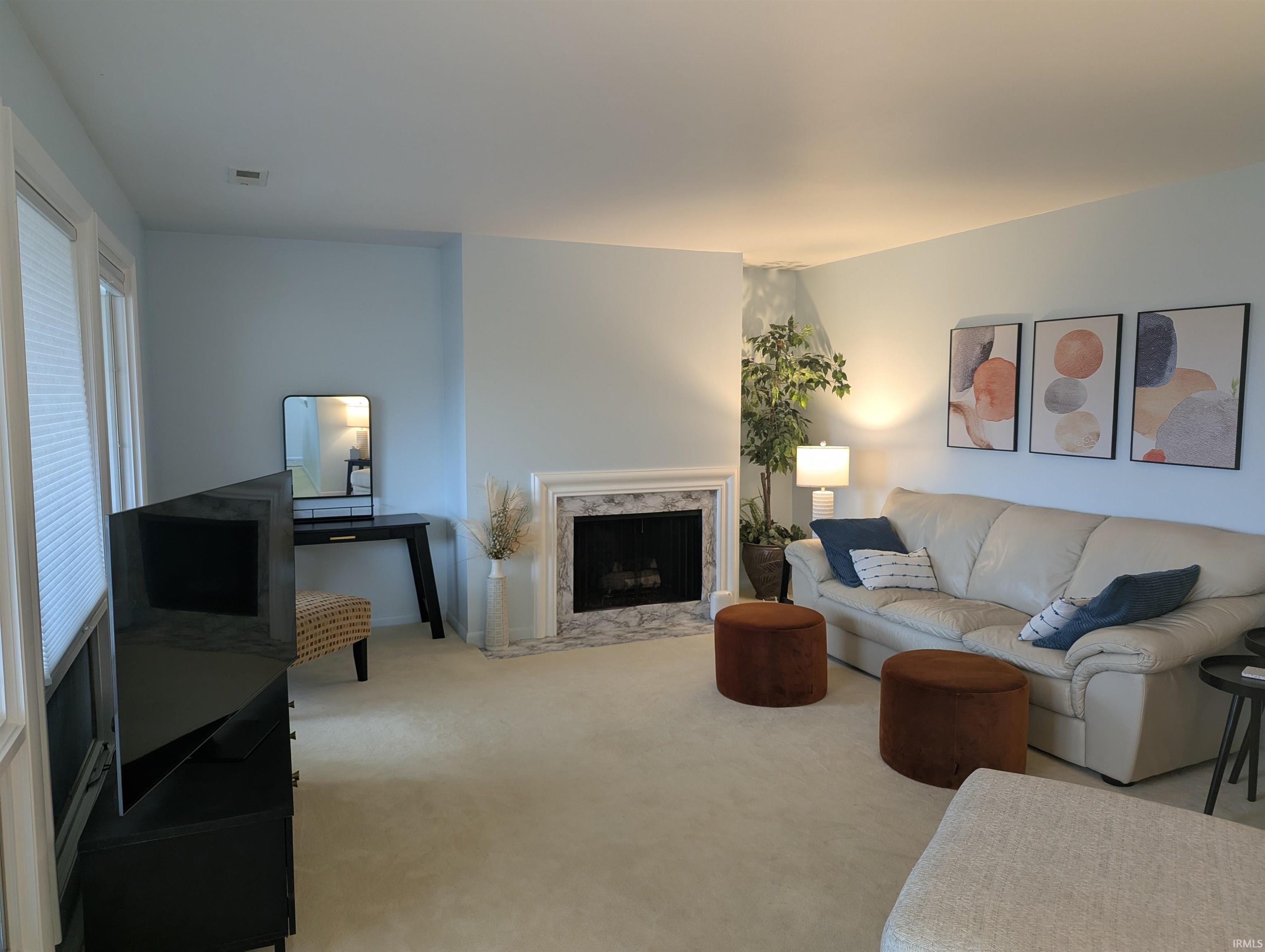 Living room featuring light carpet, a fireplace, and vaulted ceiling