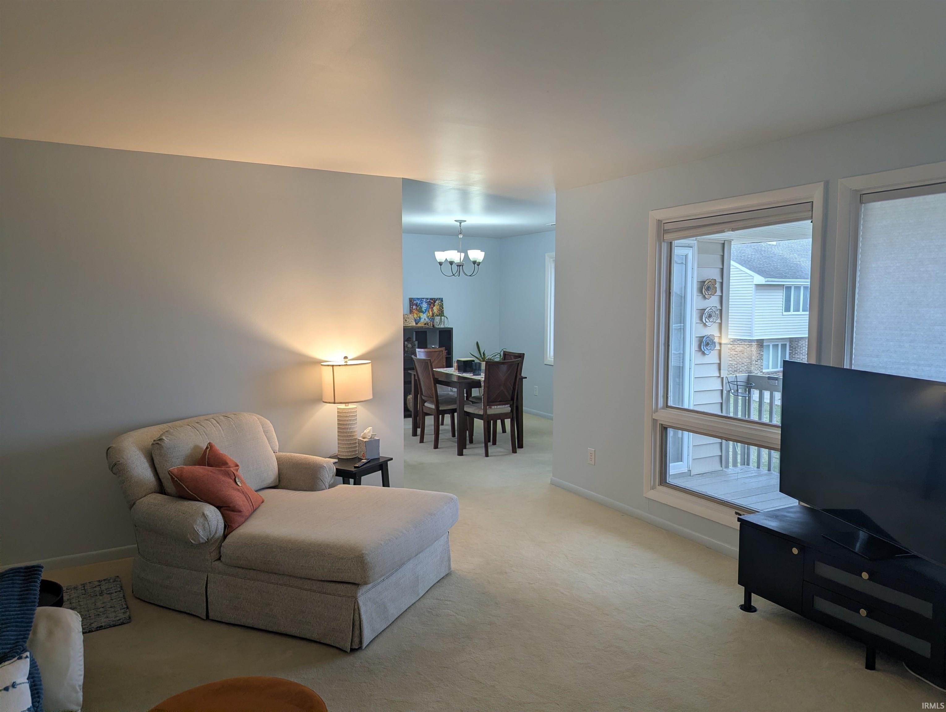 Living room featuring light colored carpet and hanging lights