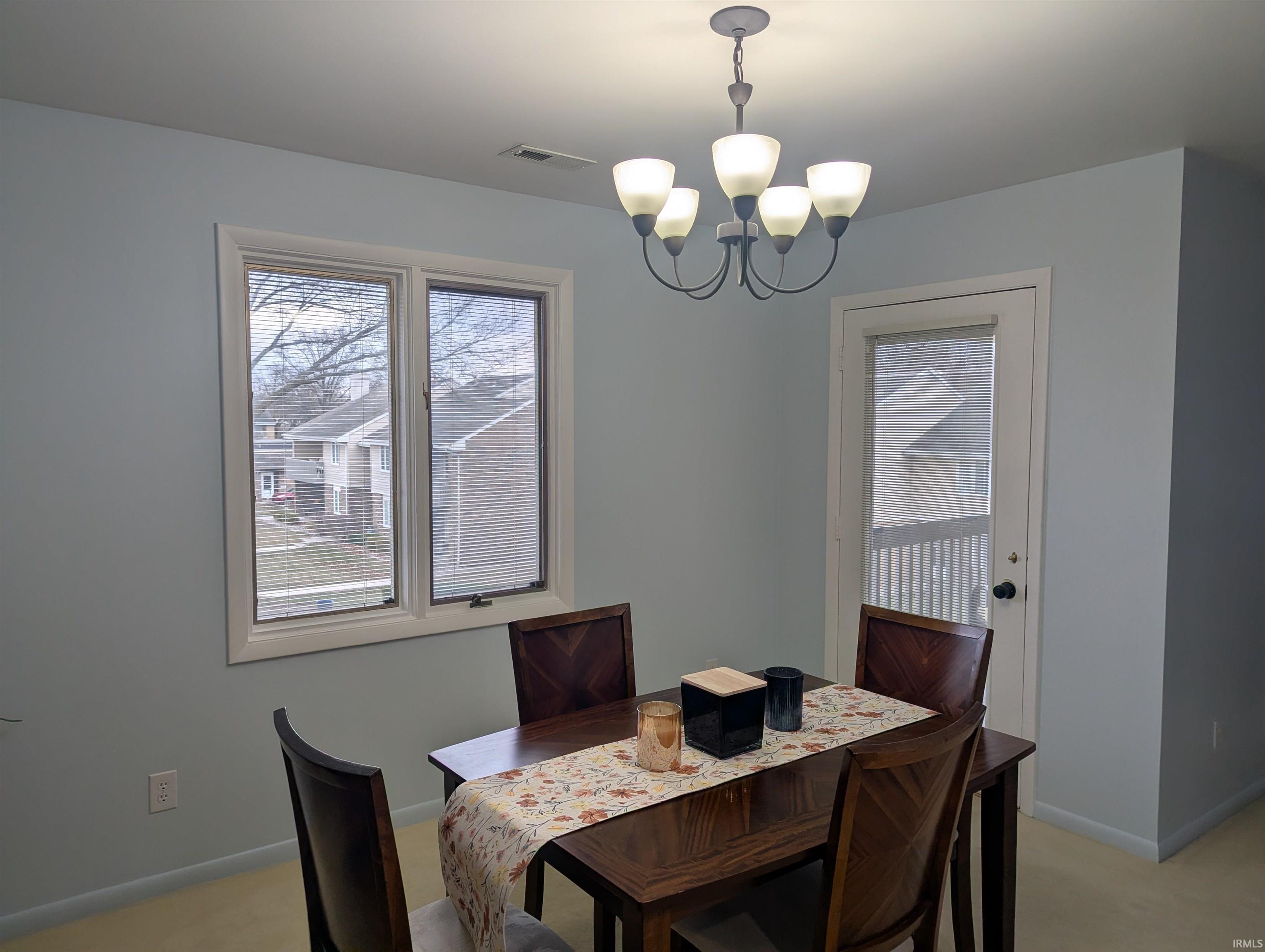 Dining area featuring suspended lighting and light colored carpet