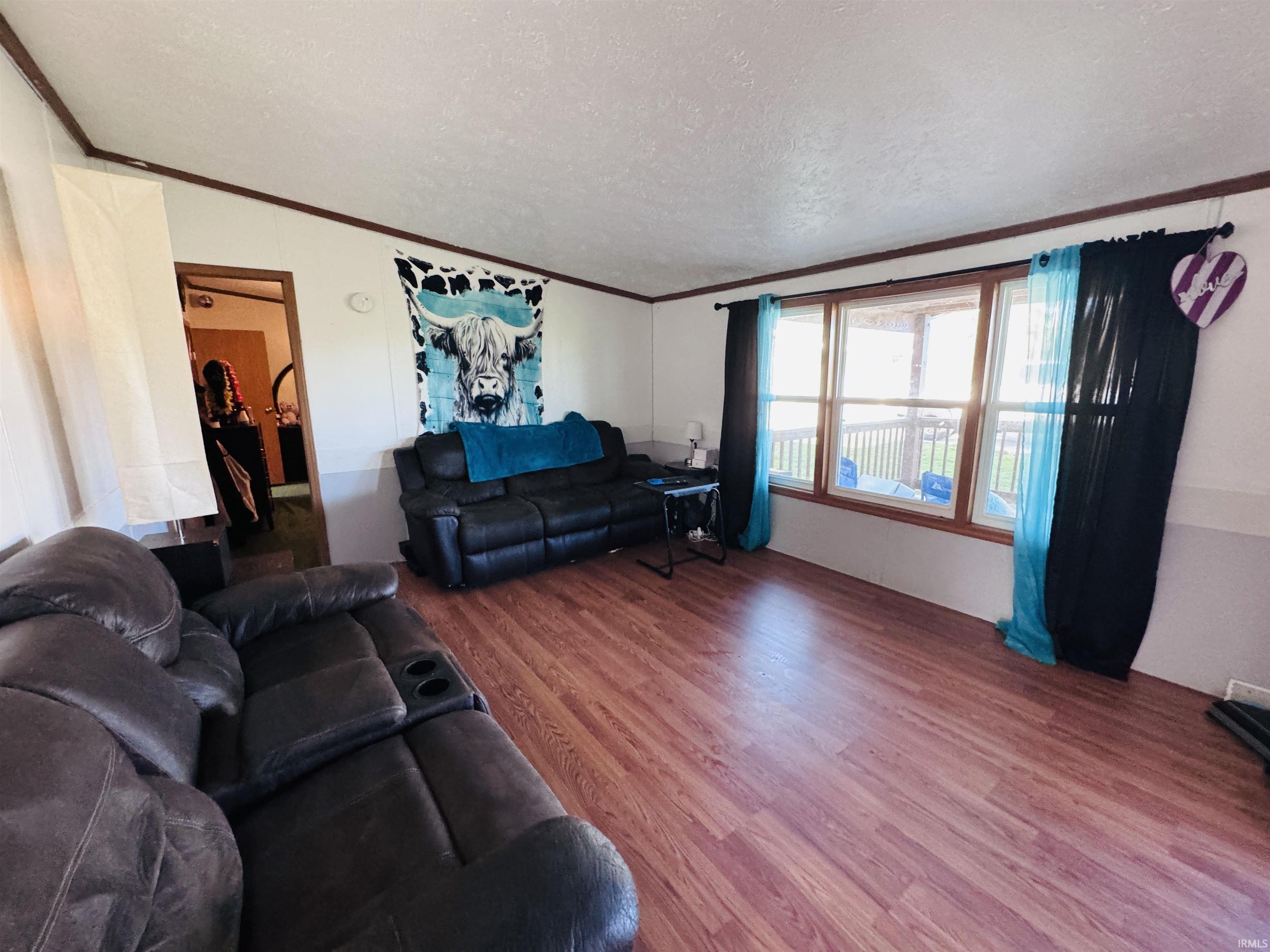 Living room featuring a textured ceiling, wood finished floors, and ornamental molding
