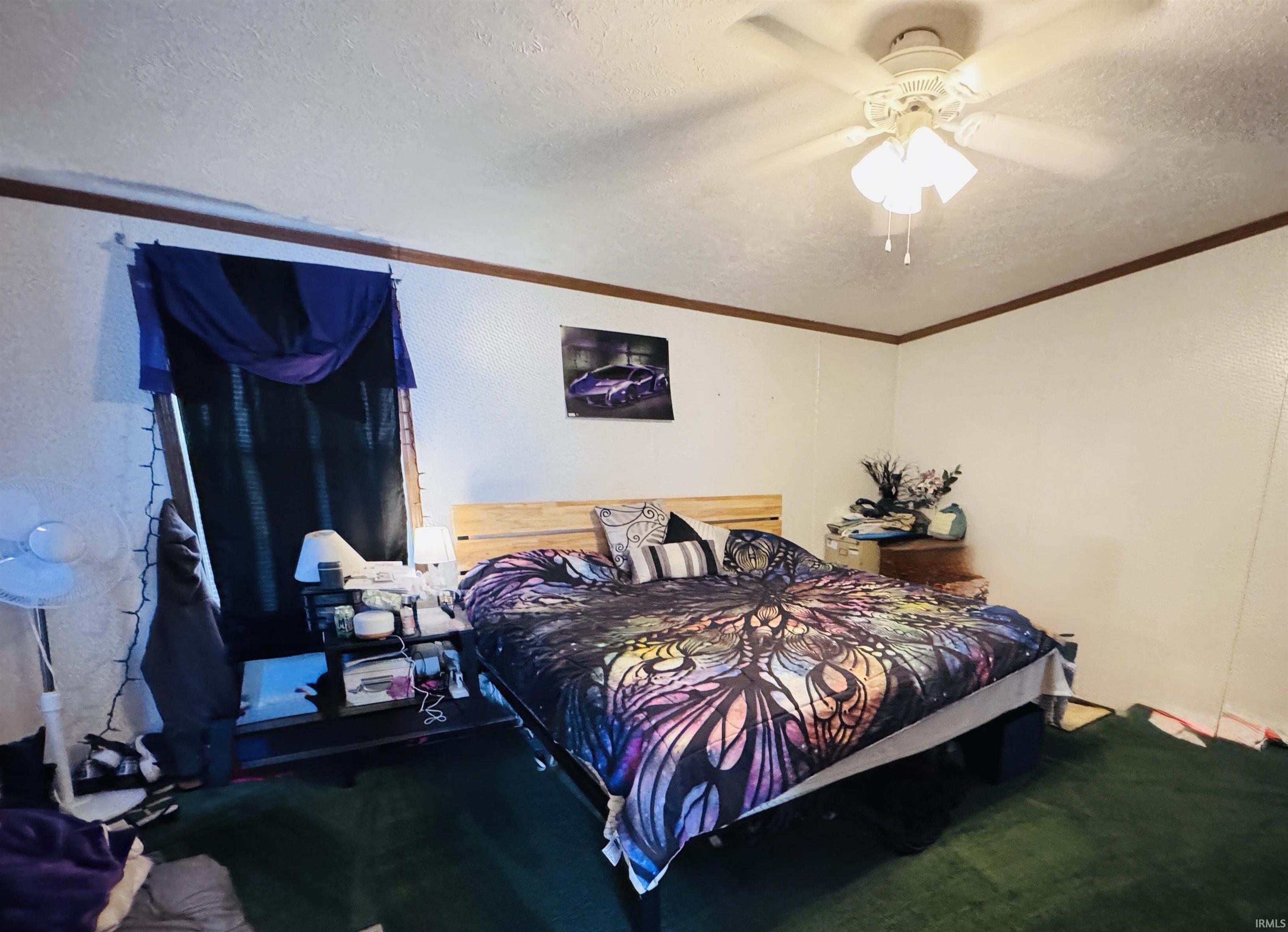 Carpeted bedroom featuring a textured ceiling, a ceiling fan, and a textured wall