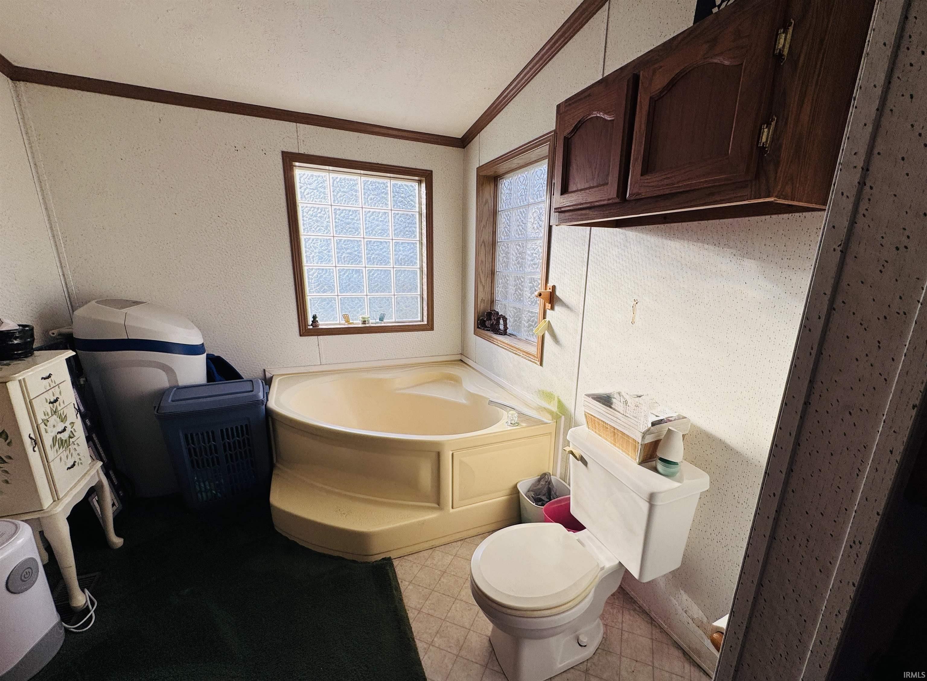 Bathroom featuring a garden tub, light flooring, and crown molding