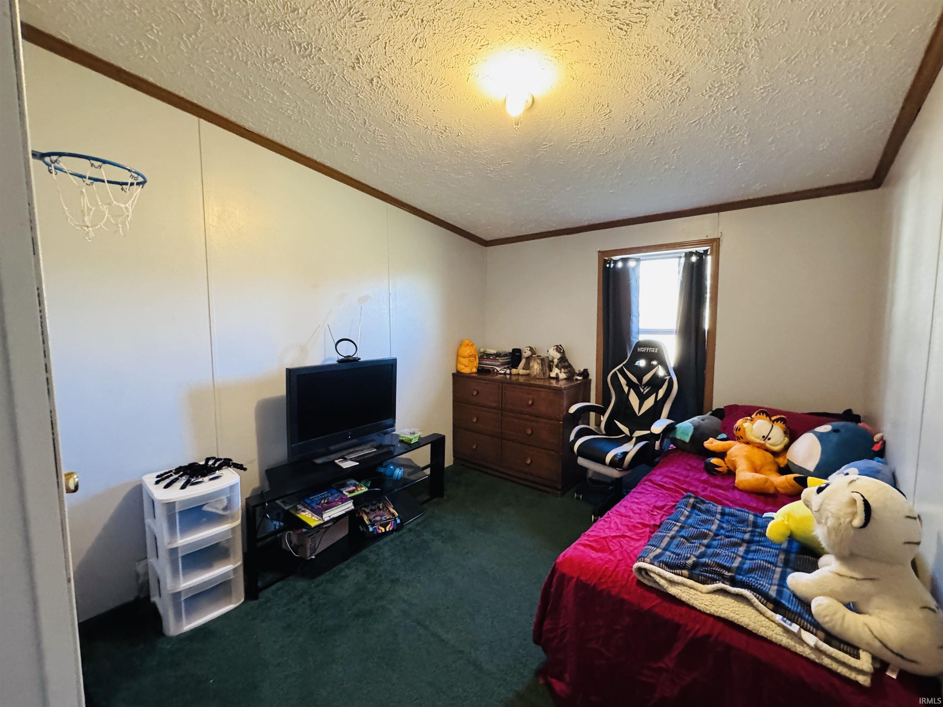 Bedroom featuring a textured ceiling, dark carpet, and crown molding