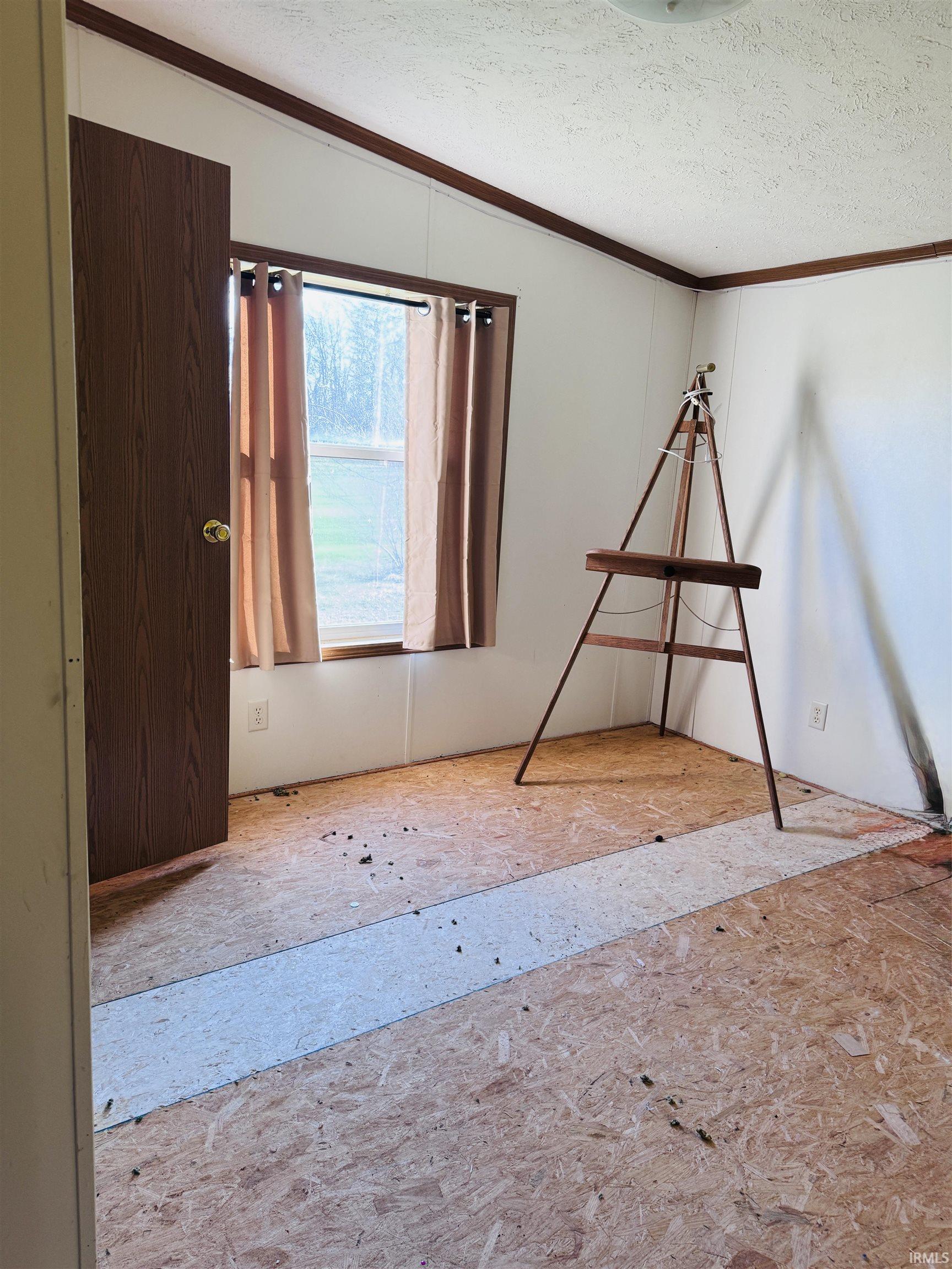 Unfurnished room with ornamental molding and a textured ceiling