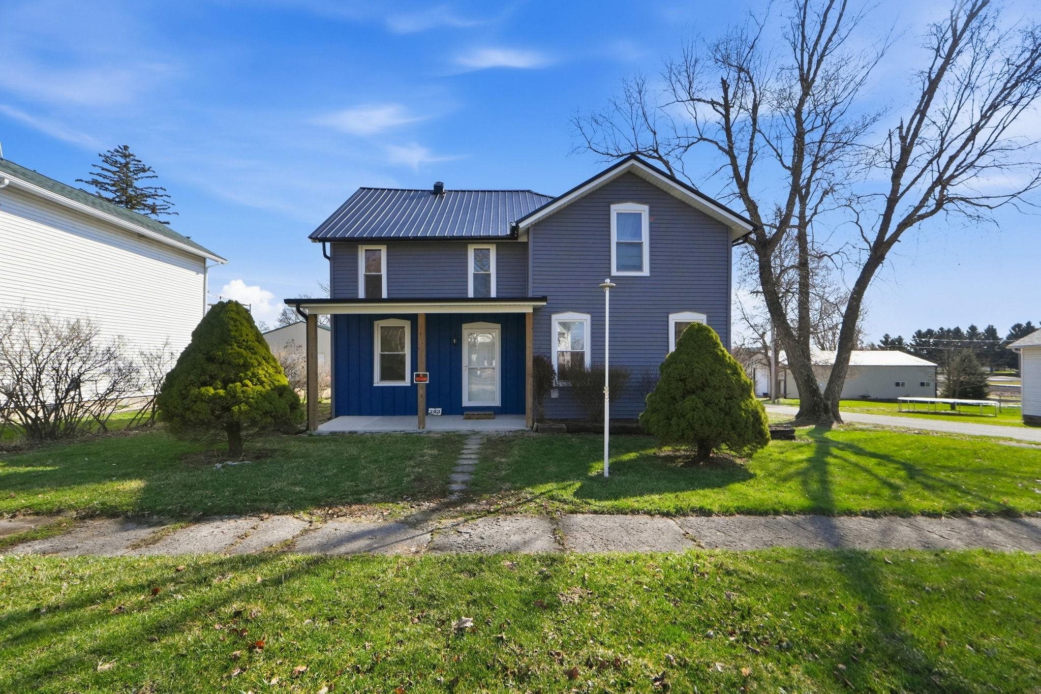 Traditional home with covered porch, a metal roof, board and batten siding, and a front yard