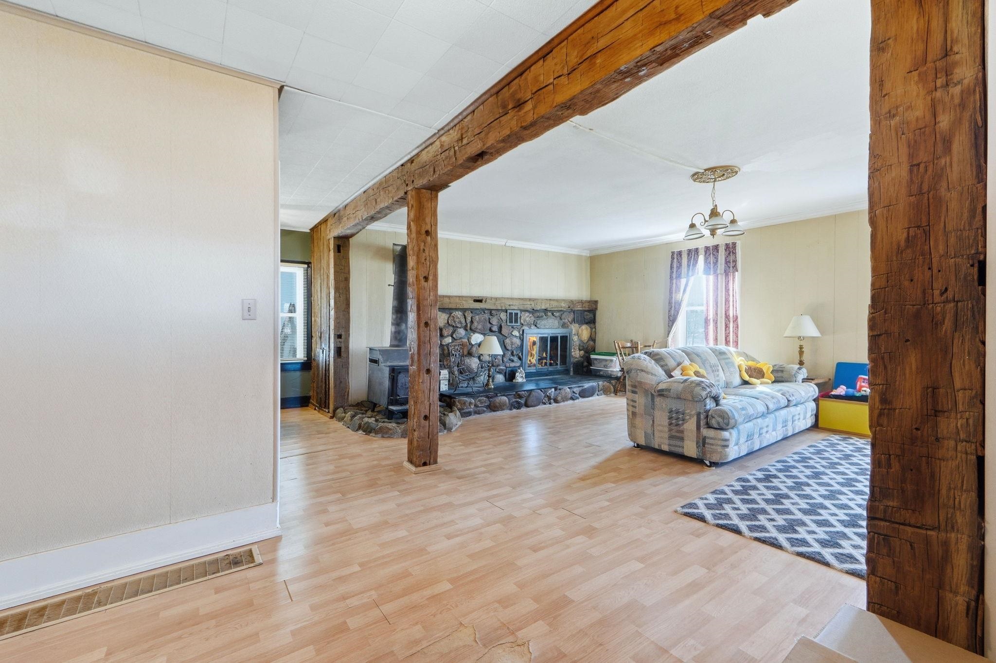 Living area featuring light wood-type flooring, beamed ceiling, and a fireplace