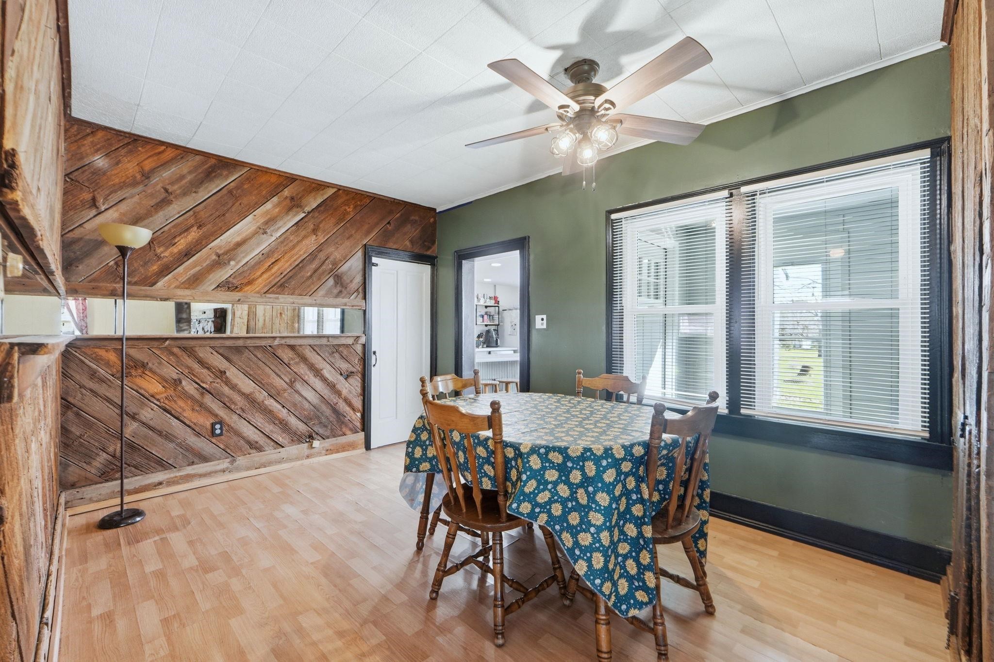 Dining room featuring wood walls, light wood-type flooring, an accent wall, and a ceiling fan