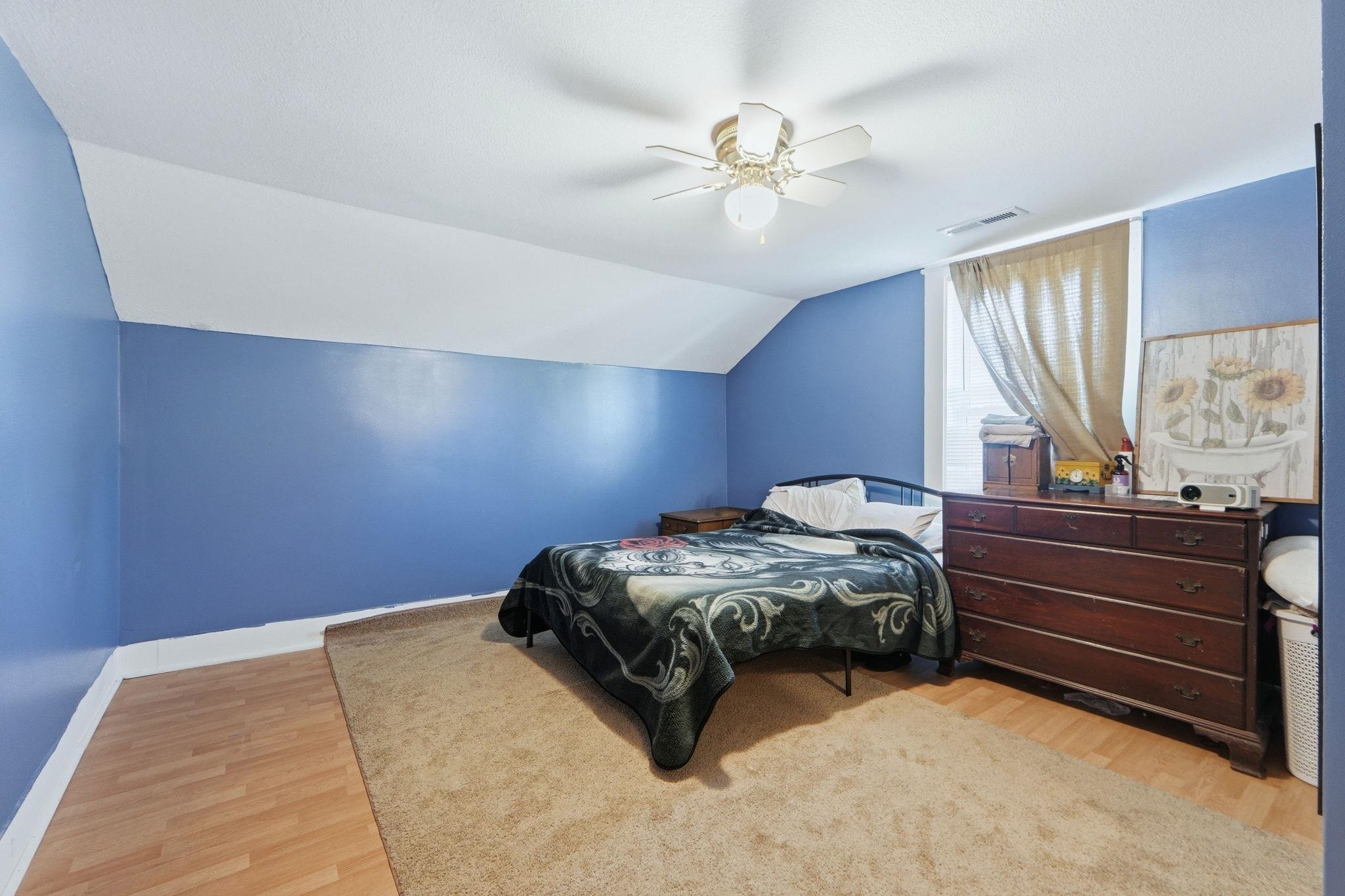 Bedroom featuring light wood-type flooring, vaulted ceiling, and a ceiling fan