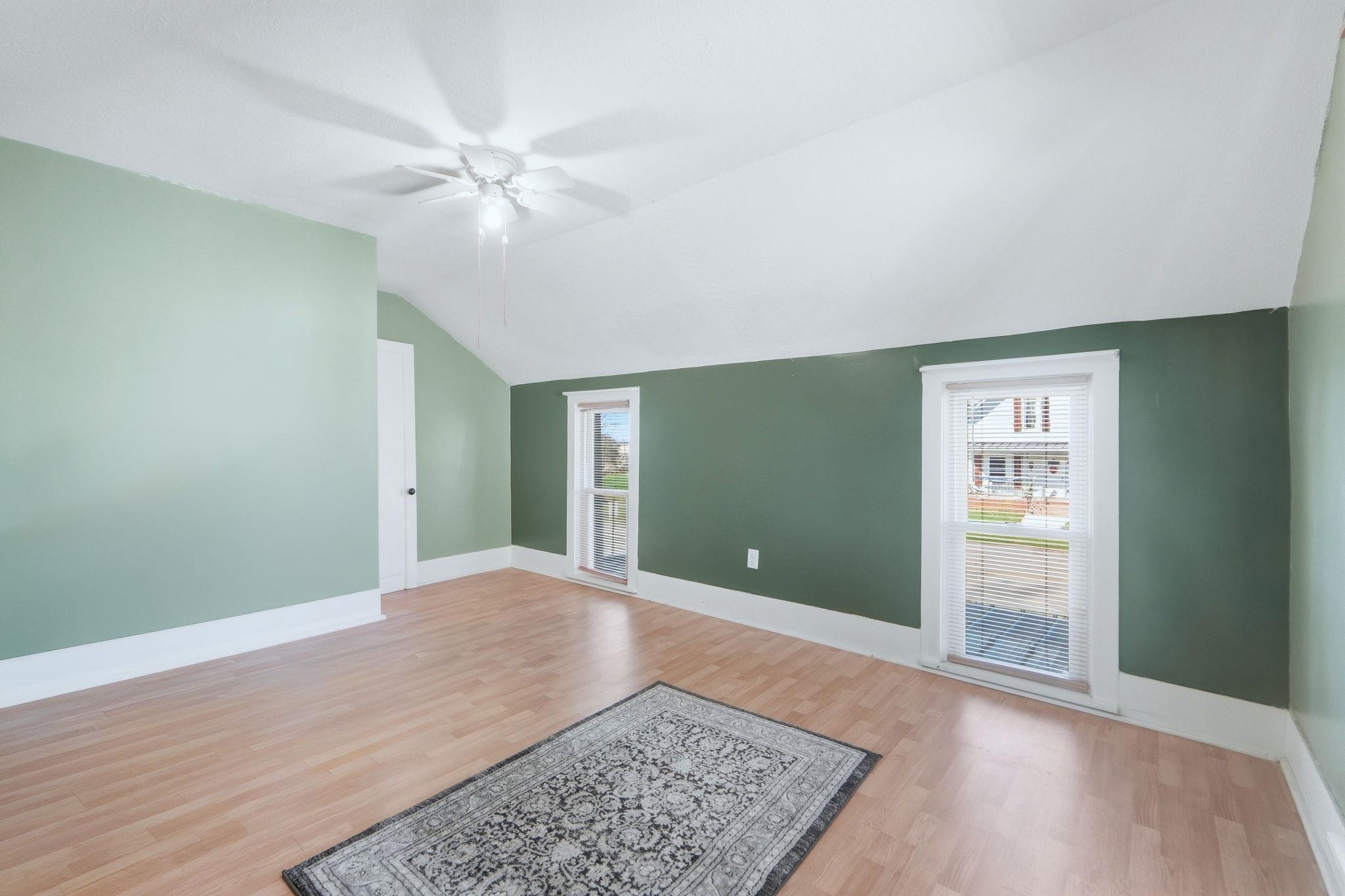 Unfurnished living room with light wood-style flooring, ceiling fan, vaulted ceiling, and plenty of natural light