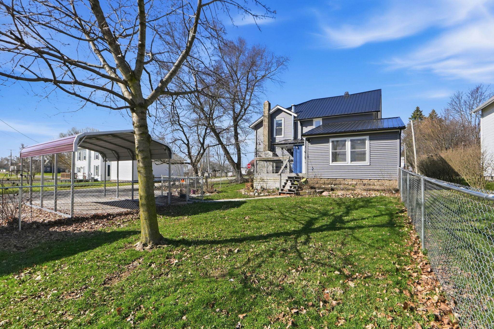 Rear view of house featuring a metal roof, a carport, and a chimney