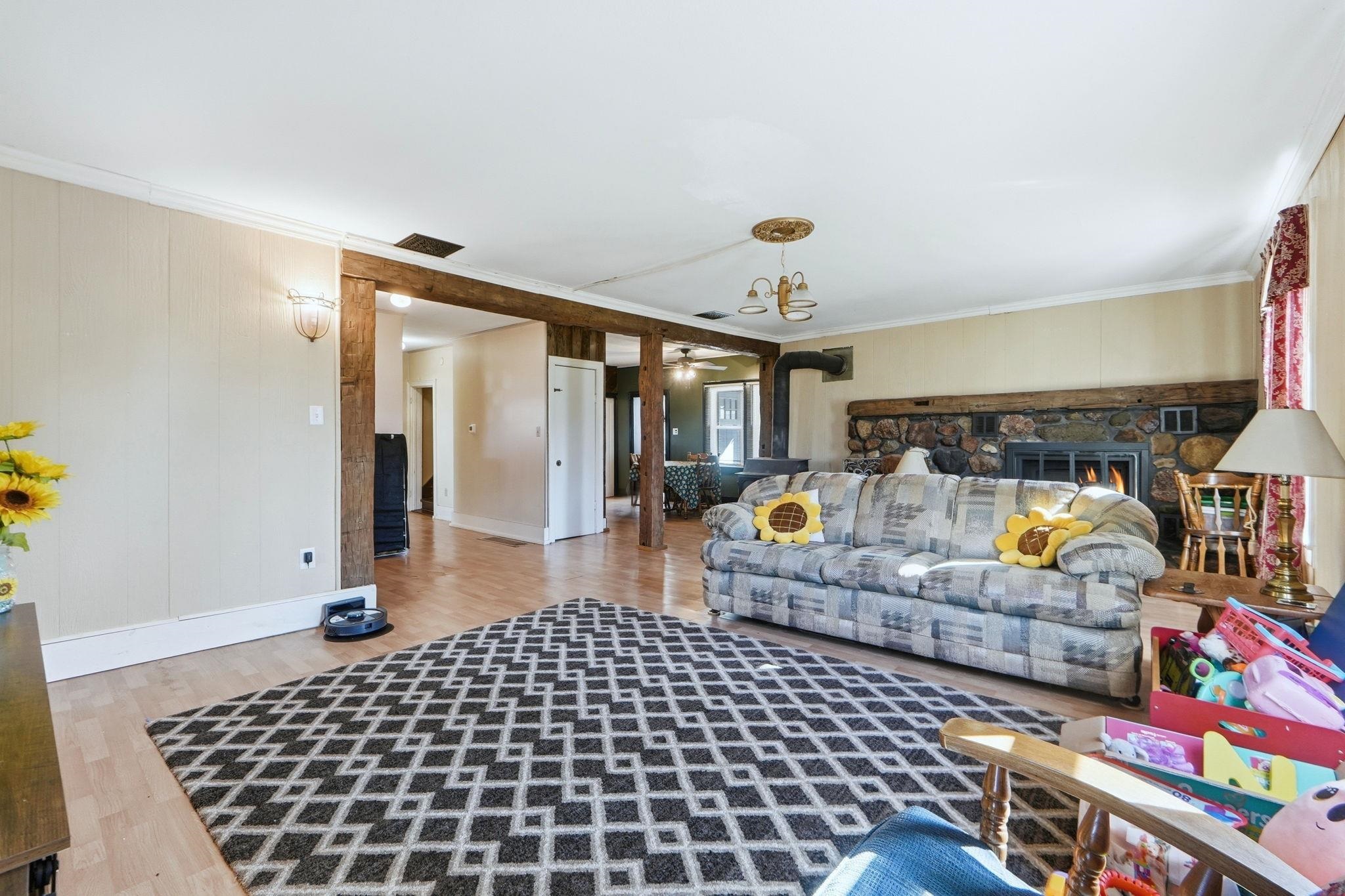 Living room featuring light wood finished floors, crown molding, a fireplace, and ceiling fan