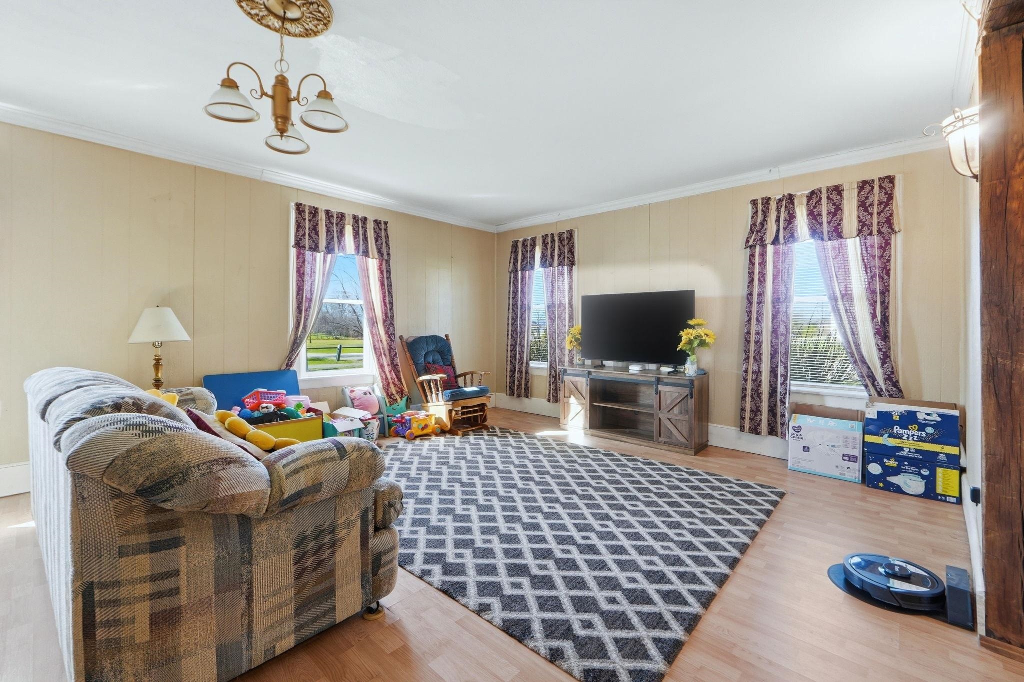 Living area with light wood-style floors, hanging lights, and ornamental molding