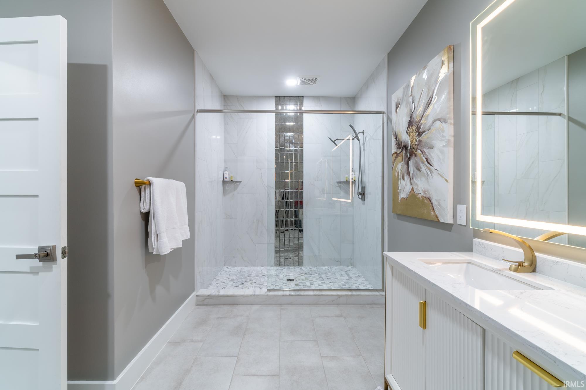Bathroom featuring vanity and a marble finish shower