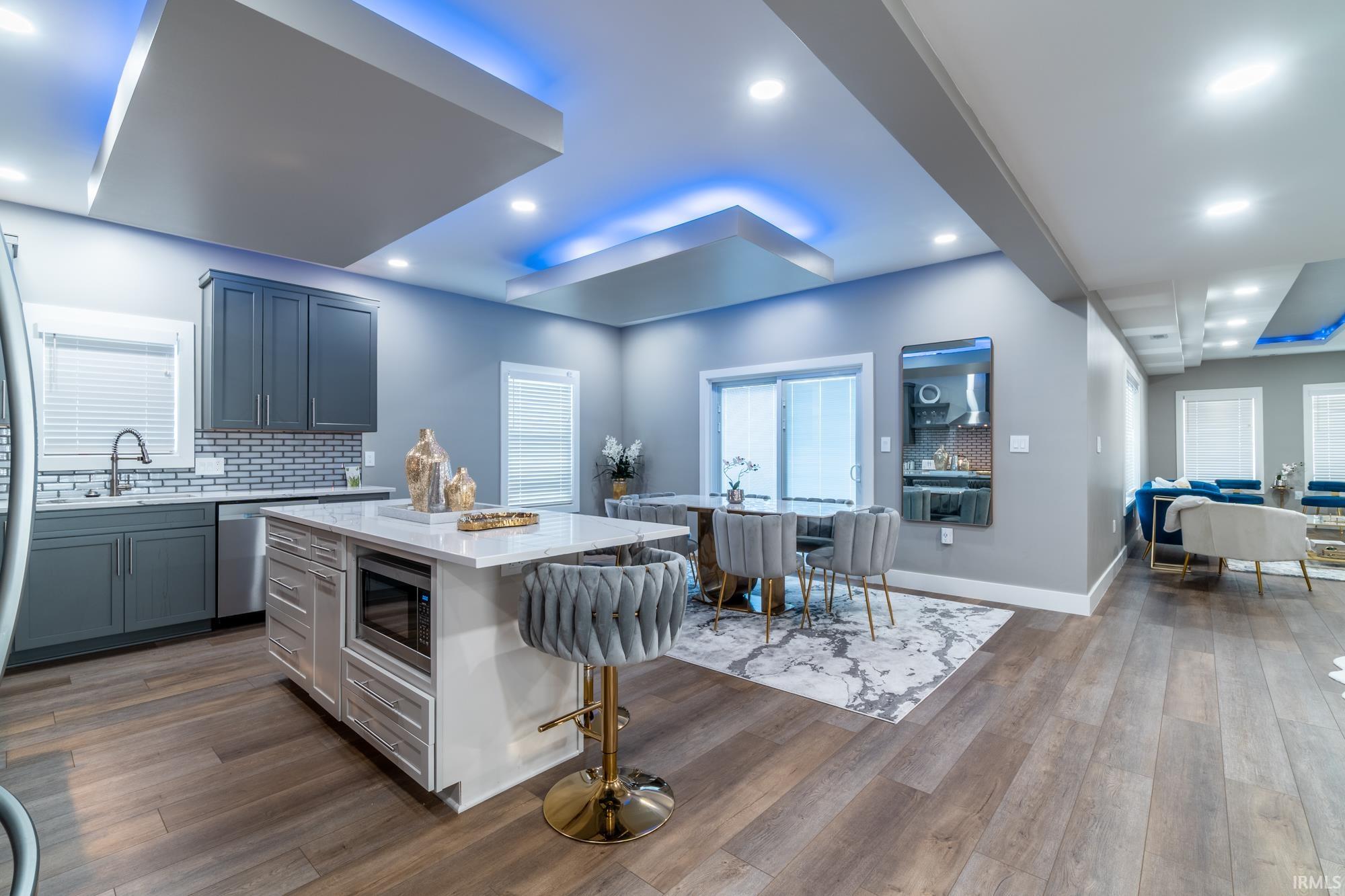 Kitchen with backsplash, a kitchen island, dark wood-style flooring, a kitchen bar, and recessed lighting