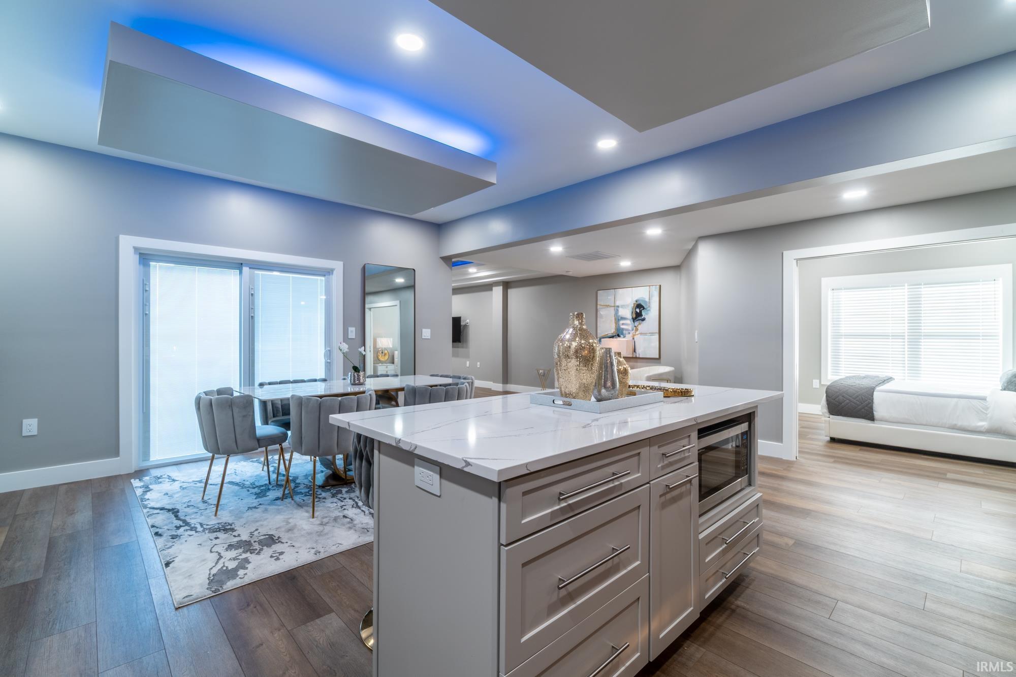 Kitchen with open floor plan, a kitchen island, light stone counters, dark wood-style flooring, and stainless steel microwave