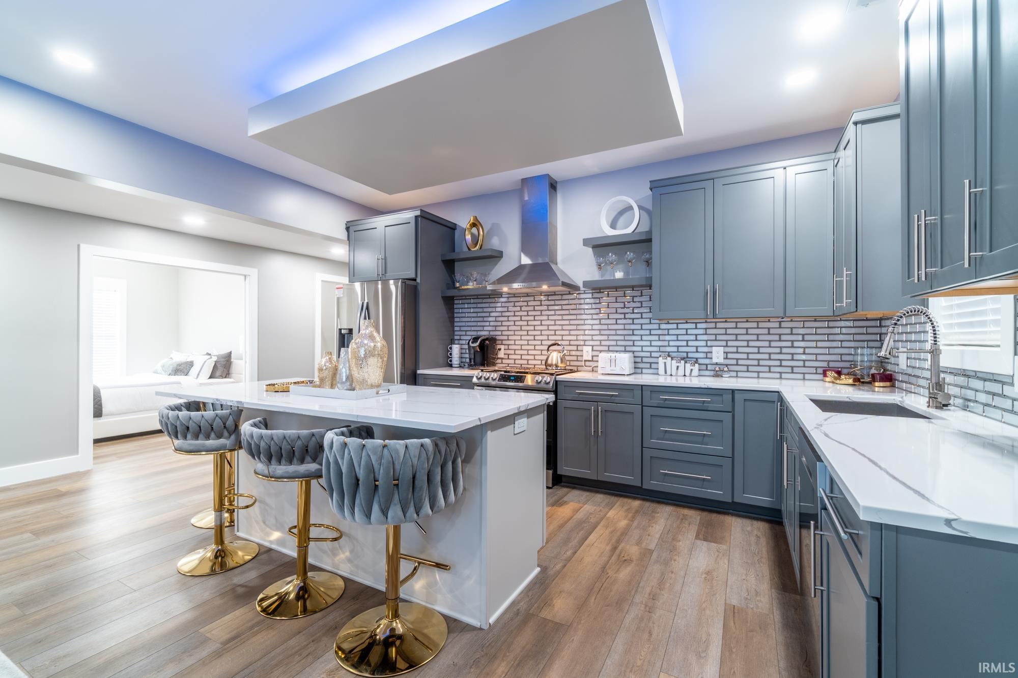 Kitchen with open shelves, a center island, light stone countertops, light wood-style floors, and recessed lighting