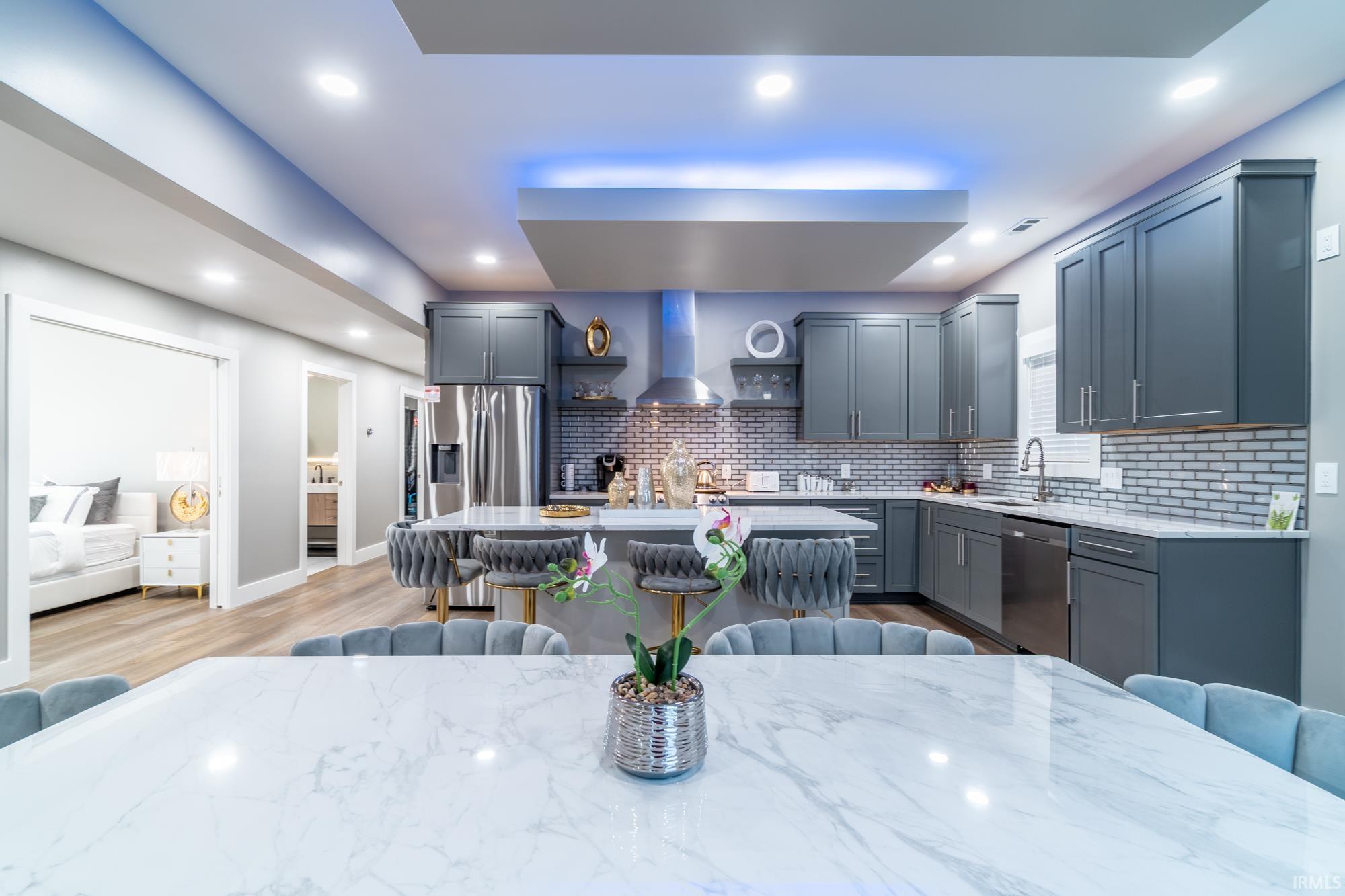 Kitchen featuring a kitchen breakfast bar, a kitchen island, gray cabinets, stainless steel appliances, and light stone countertops