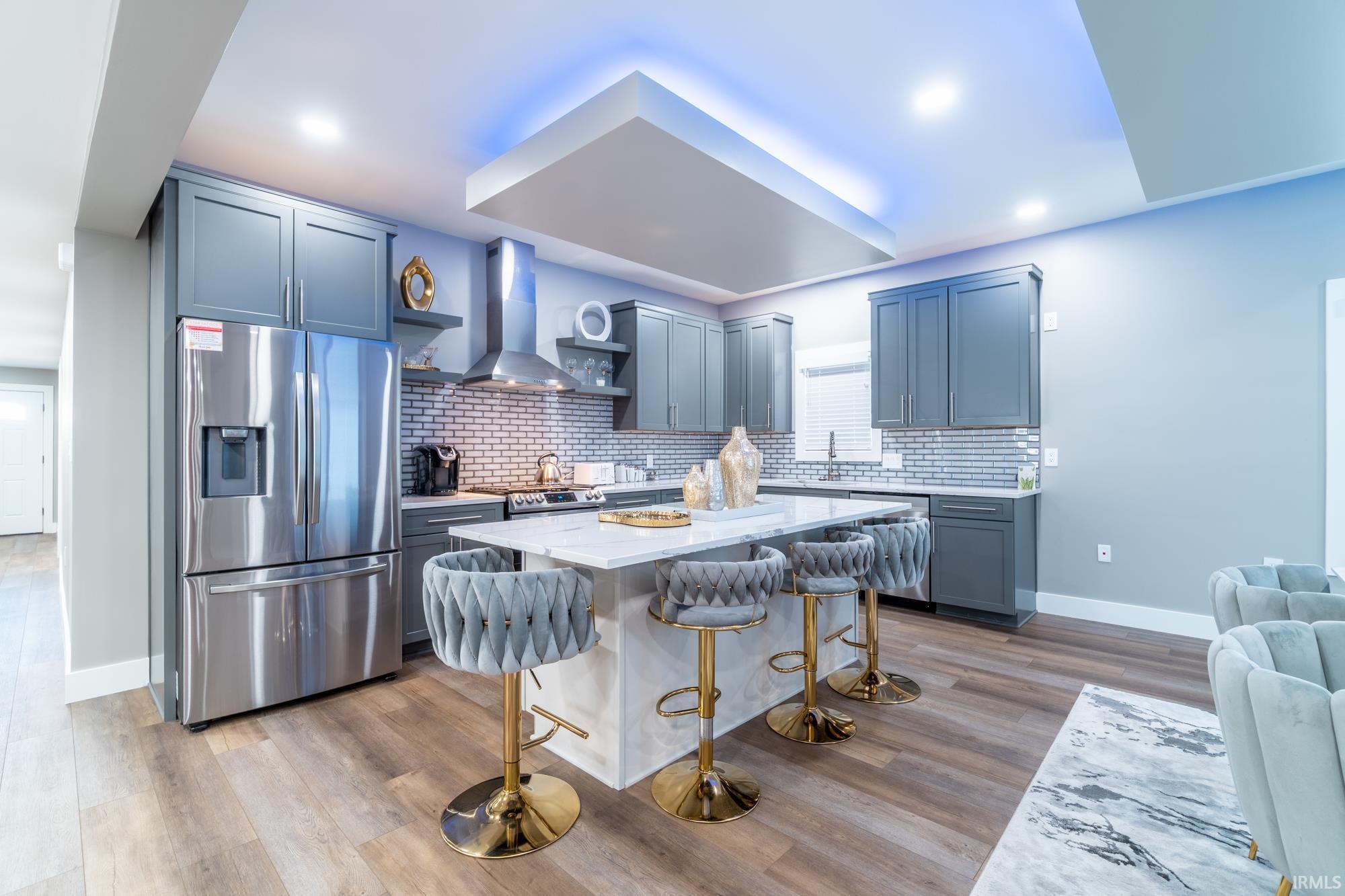 Kitchen with stainless steel appliances, decorative backsplash, light stone counters, a kitchen bar, and a center island