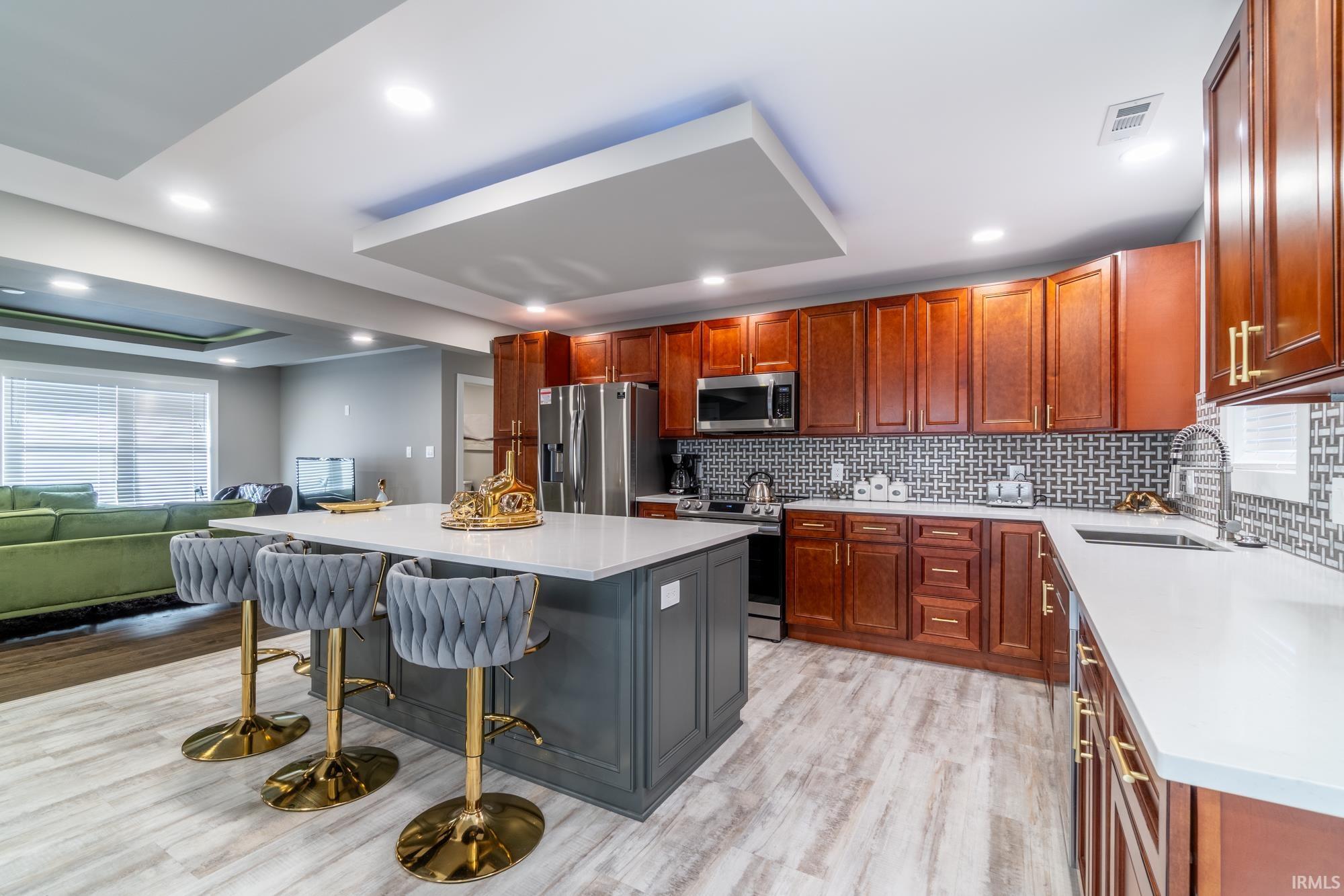 Kitchen featuring a breakfast bar area, light stone countertops, stainless steel appliances, open floor plan, and a kitchen island