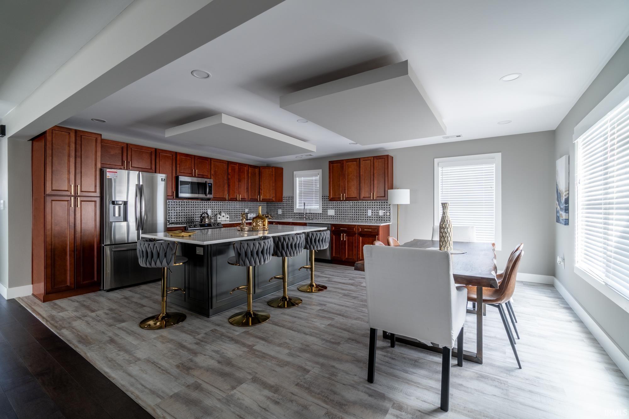 Kitchen with stainless steel appliances, a breakfast bar area, backsplash, a center island, and light wood-style floors