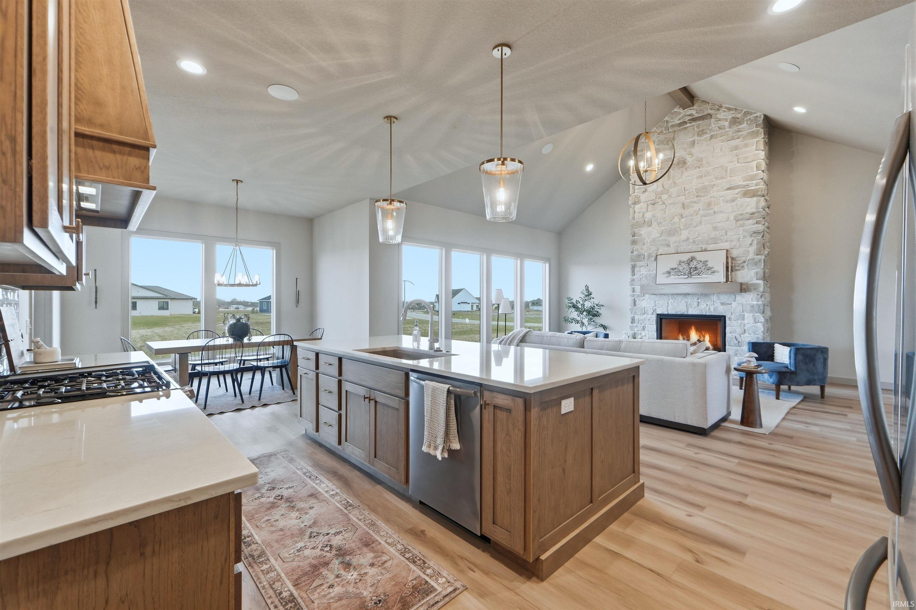 Kitchen featuring wood finish cabinets, a center island with sink, light wood finished floors, open floor plan, and a high ceiling